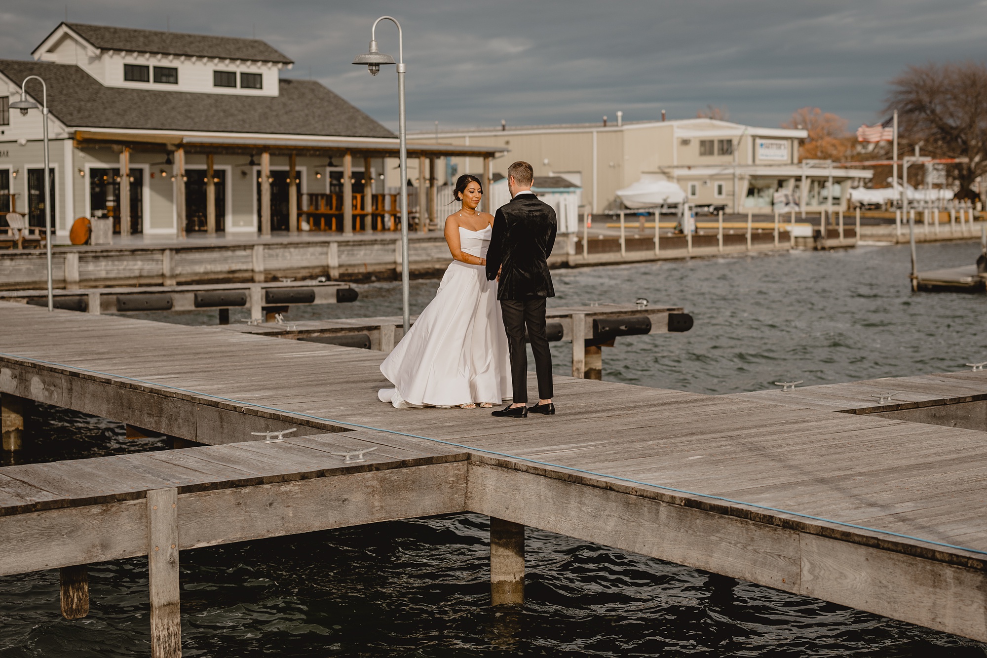 bride and groom stand in the middle of wooden dock at the Lake House at Canandaigua