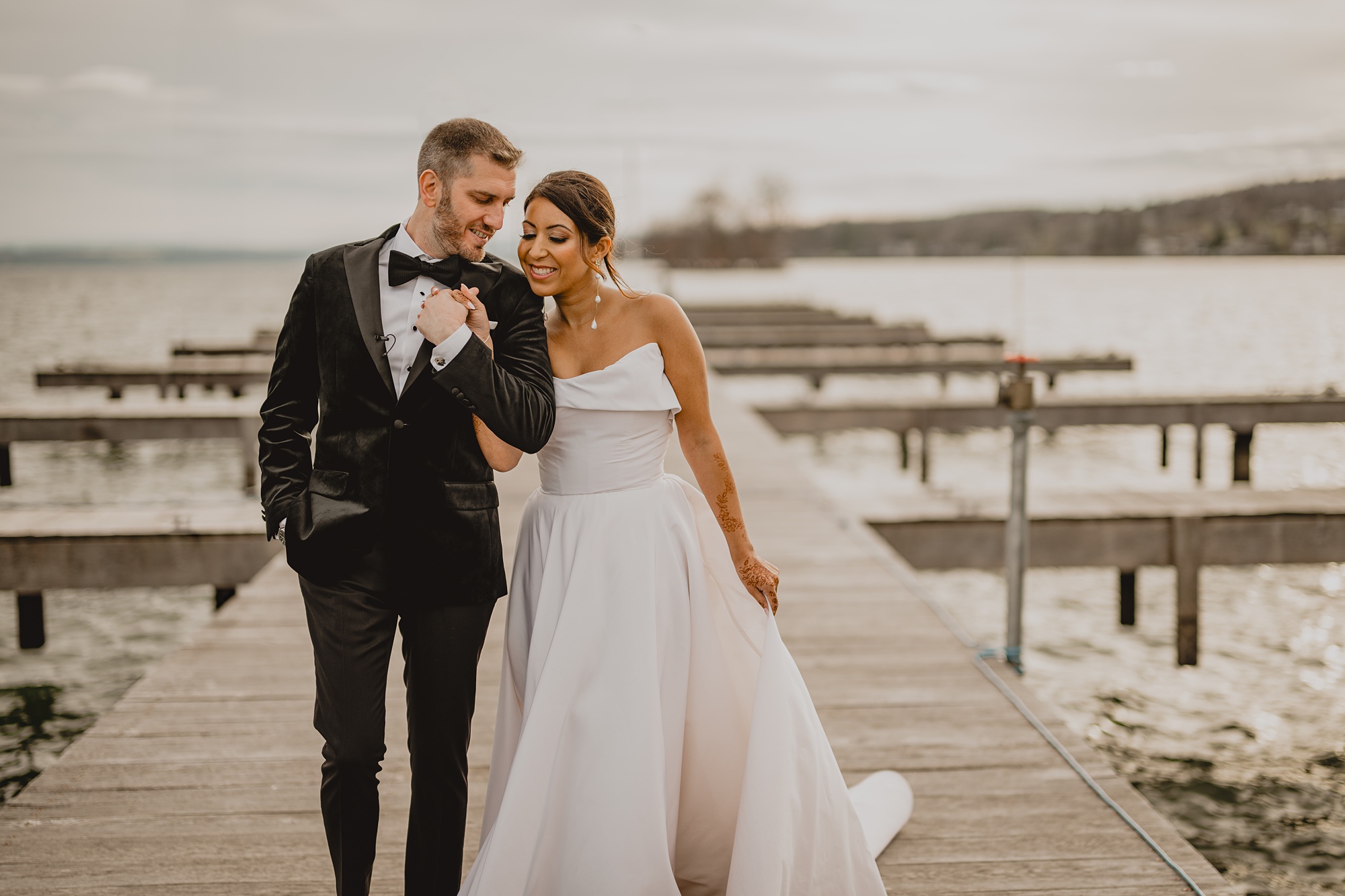 bride leans on groom's shoulder on wooden dock at the Lake House at Canandaigua