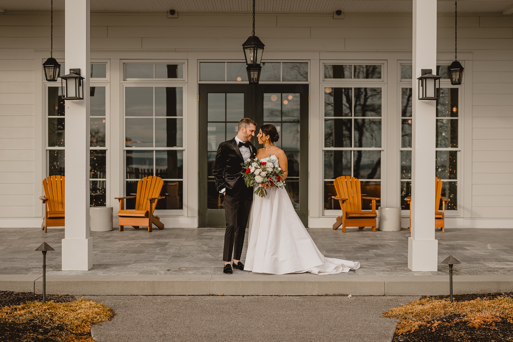 bride and groom stand on front porch of the Lake House at Canandaigua