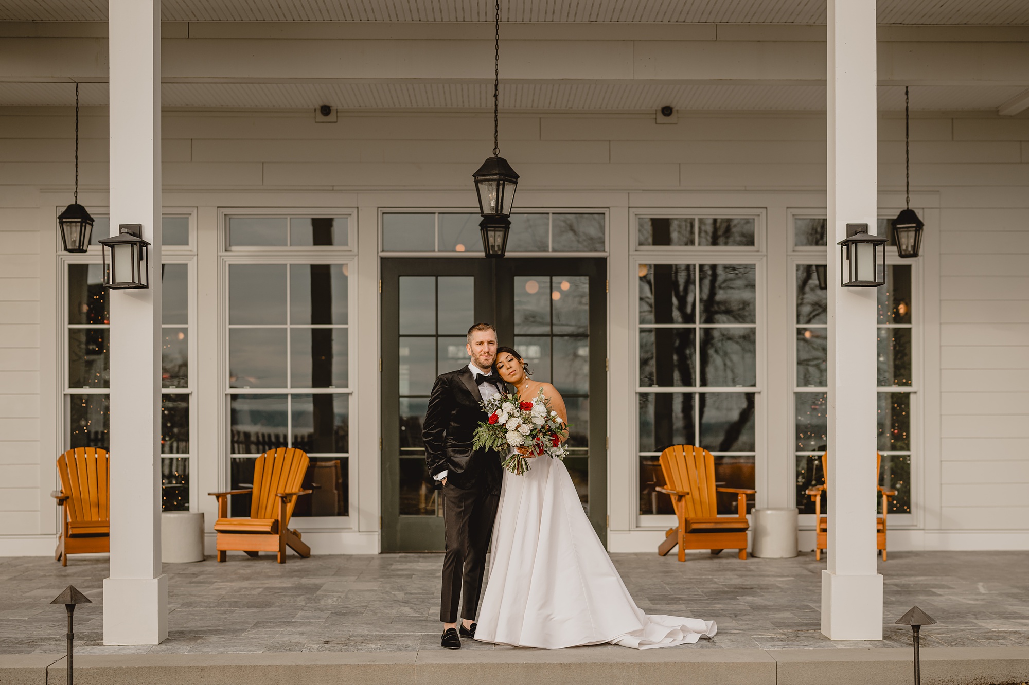 bride and groom hug on front porch of the Lake House at Canandaigua
