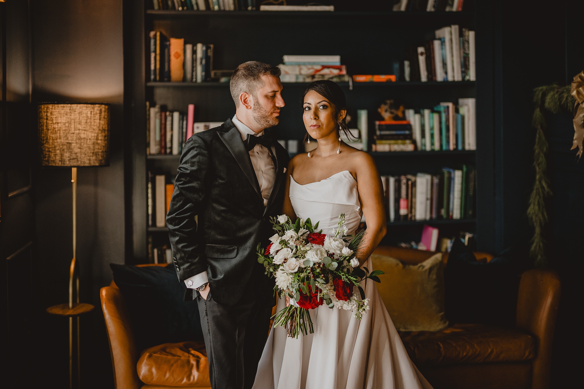 groom looks at bride standing in the library at the Lake House at Canandaigua