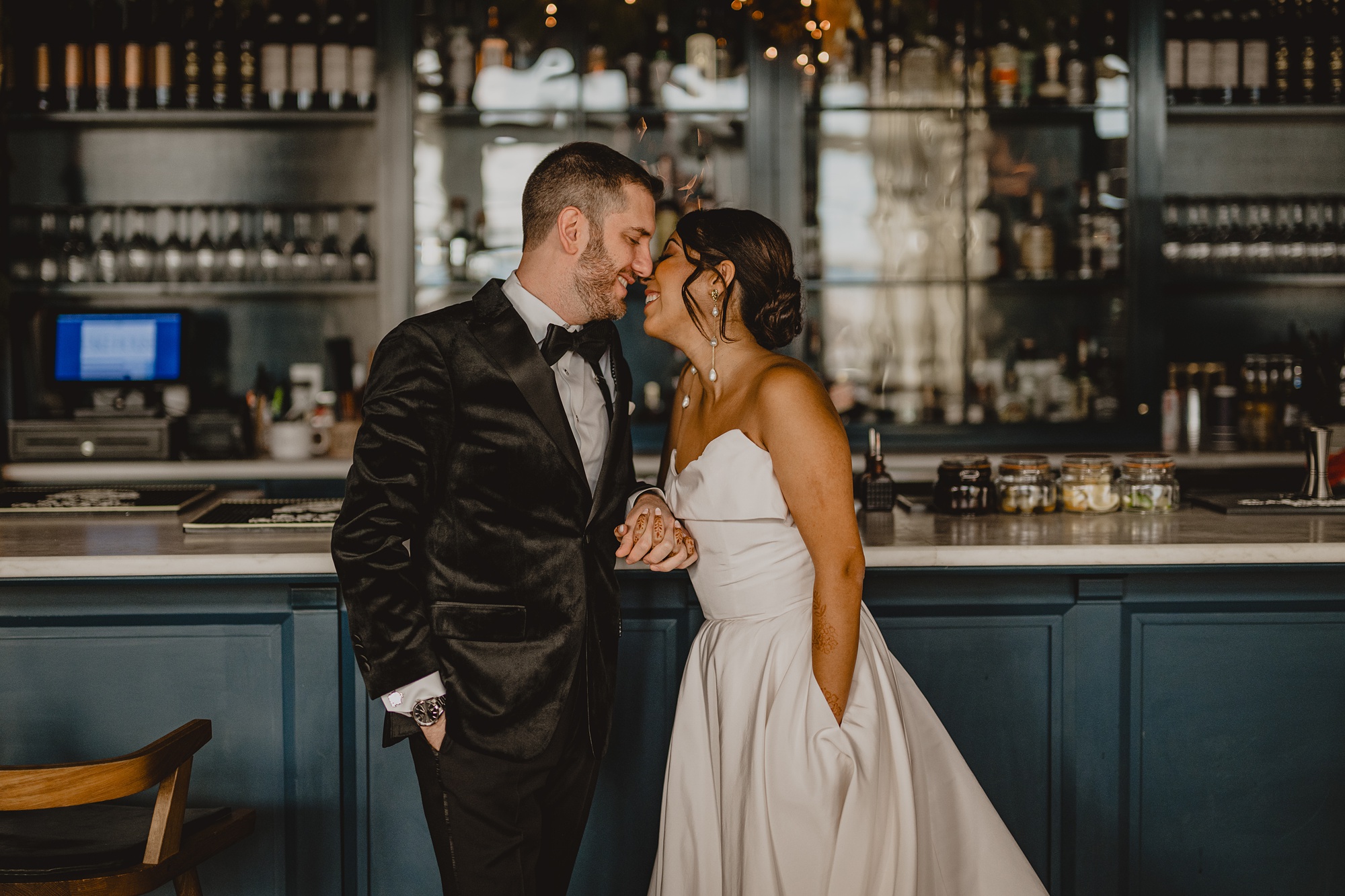 bride leans to kiss groom at the bar at the Lake House at Canandaigua