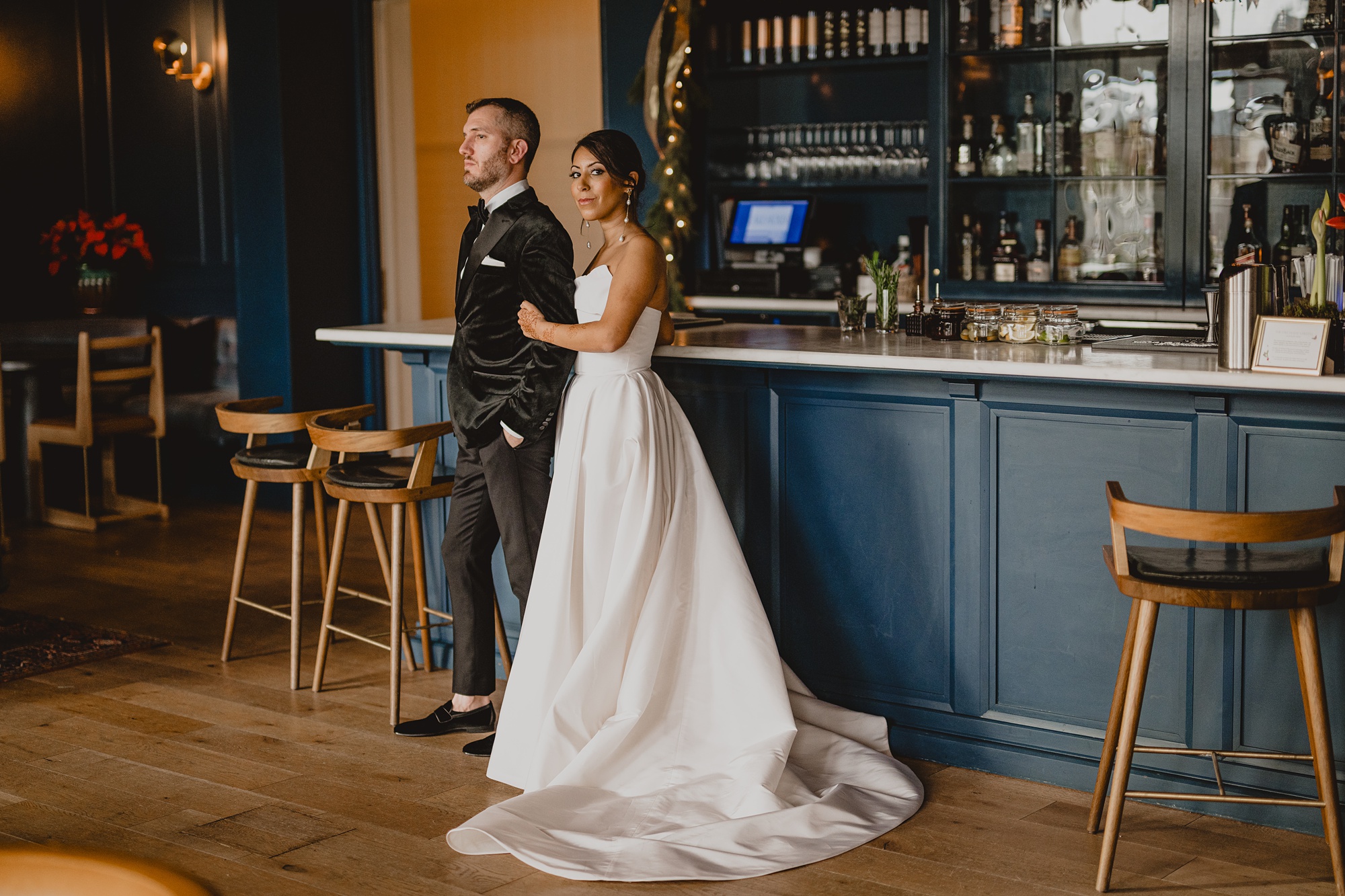 bride stands slightly behind the groom at the bar inside the Lake House at Canandaigua