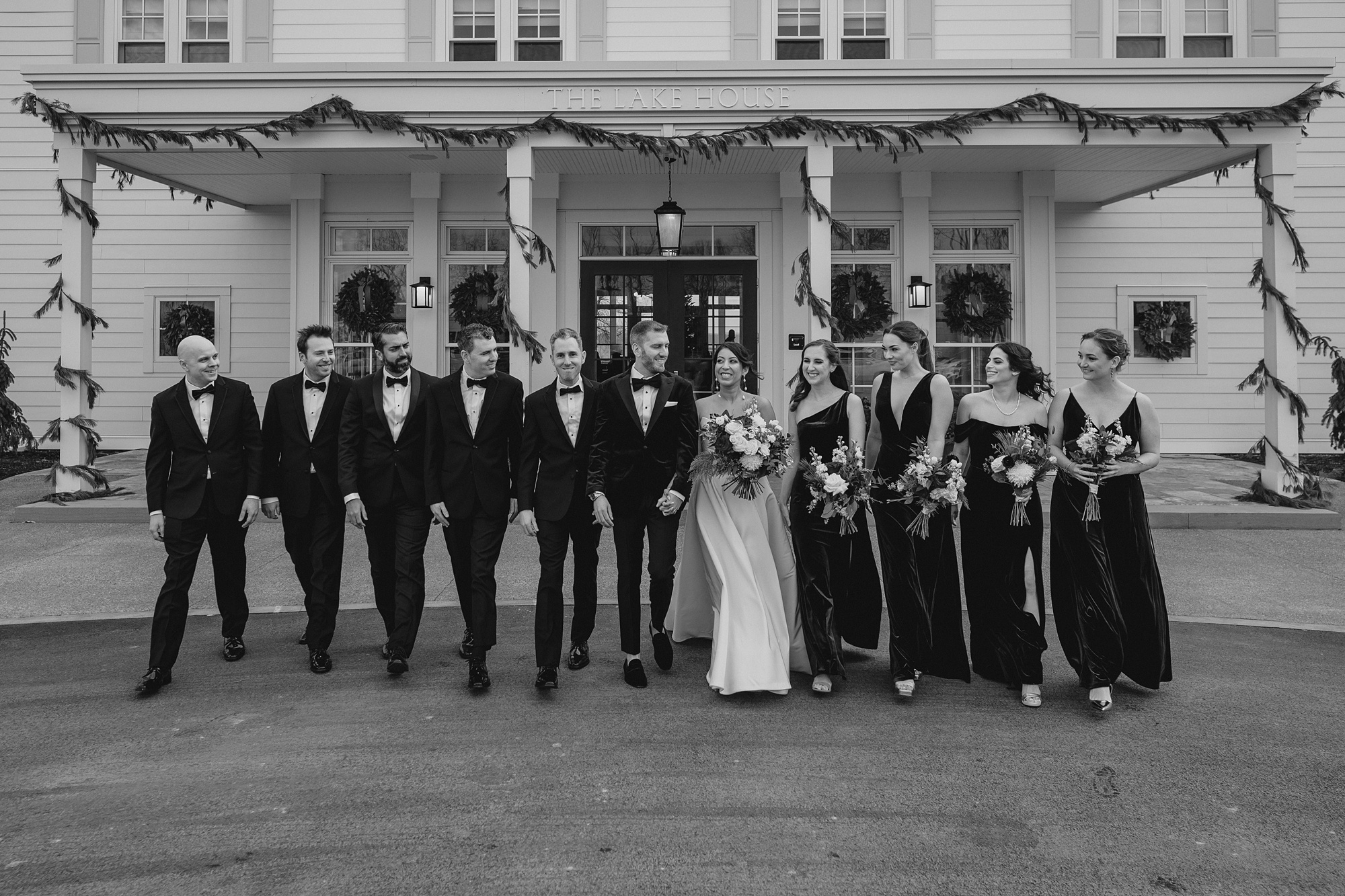 bride and groom walk with wedding party outside the Lake House at Canandaigua