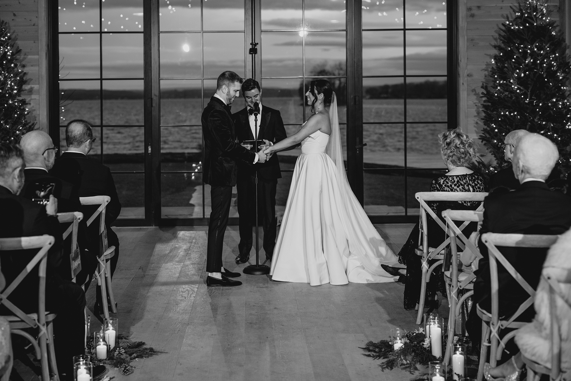 bride and groom hold hands standing at the end of the aisle at the Lake House at Canandaigua