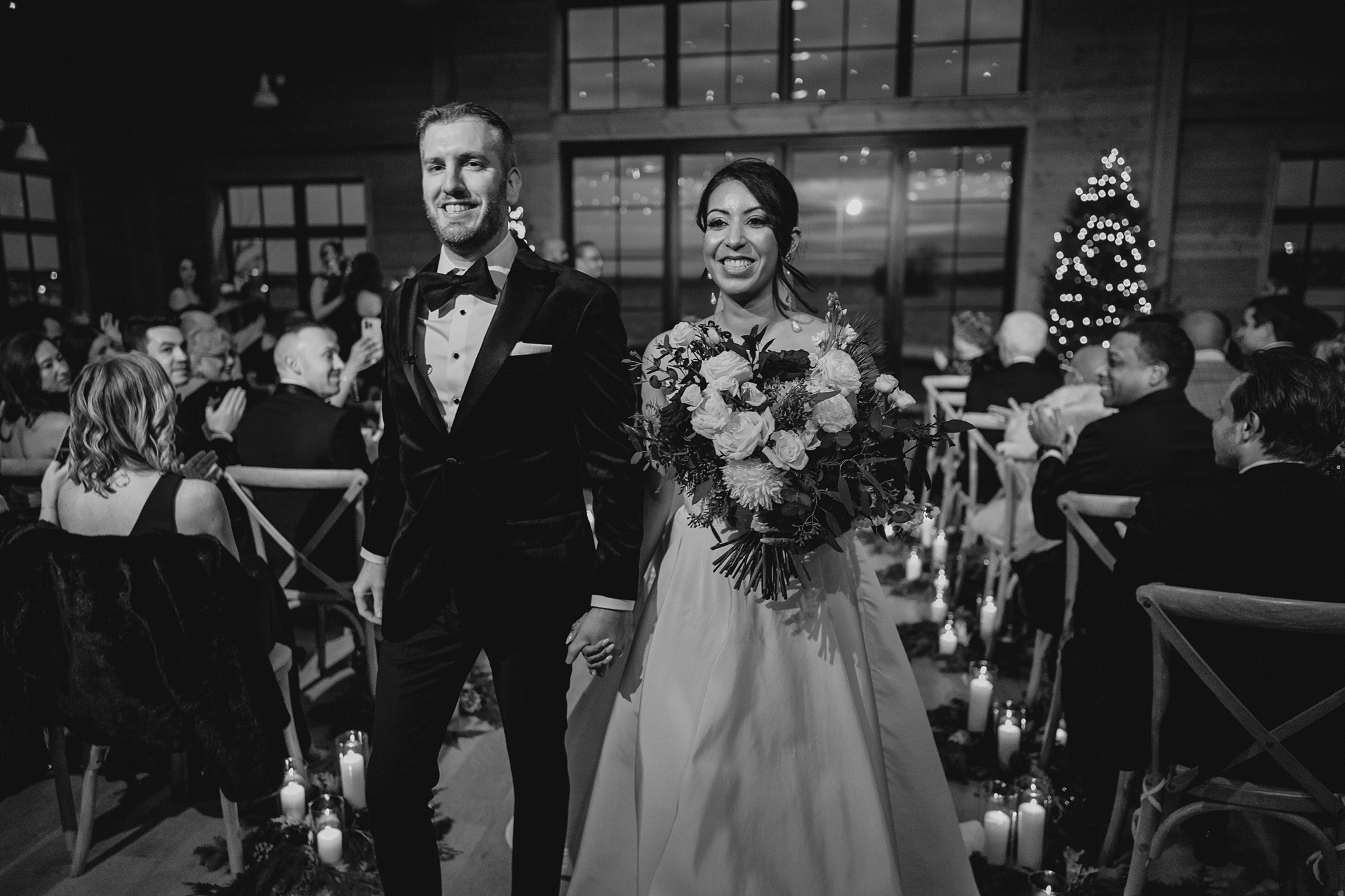 bride and groom smile walking up aisle lined with candles after ceremony at the Lake House at Canandaigua