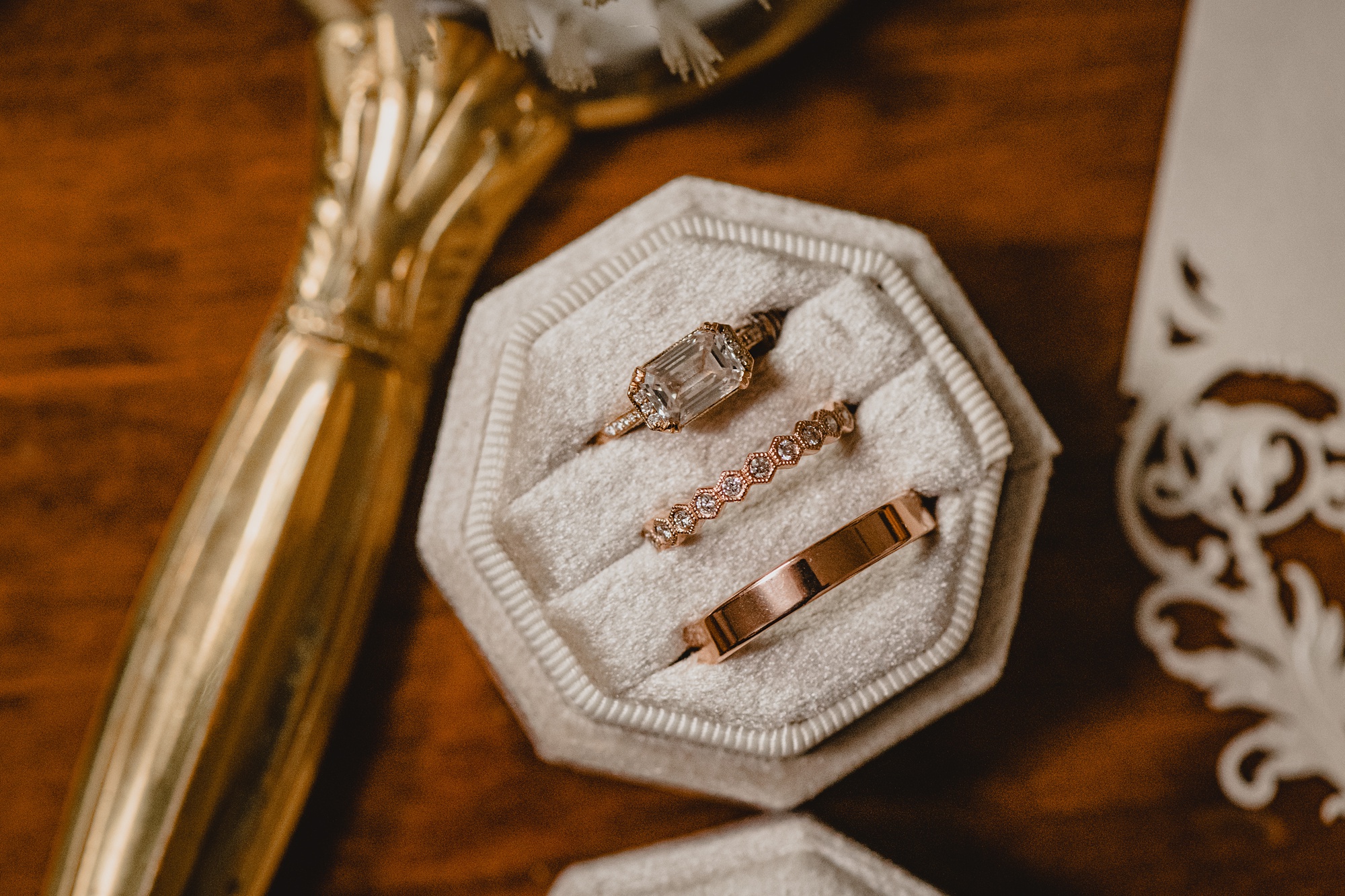 gold wedding bands rest in ivory ring box on wooden table