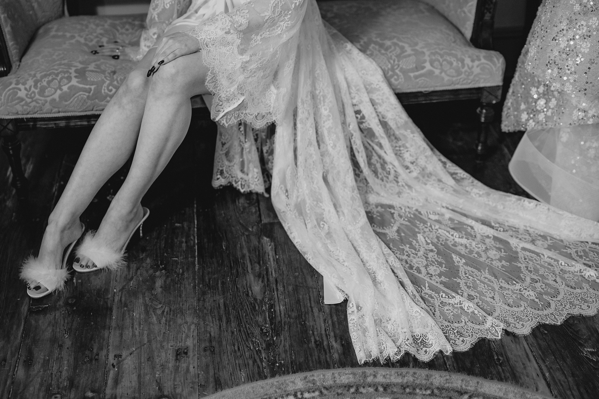 bride sits on sofa with lace robe and fuzzy heeled slippers