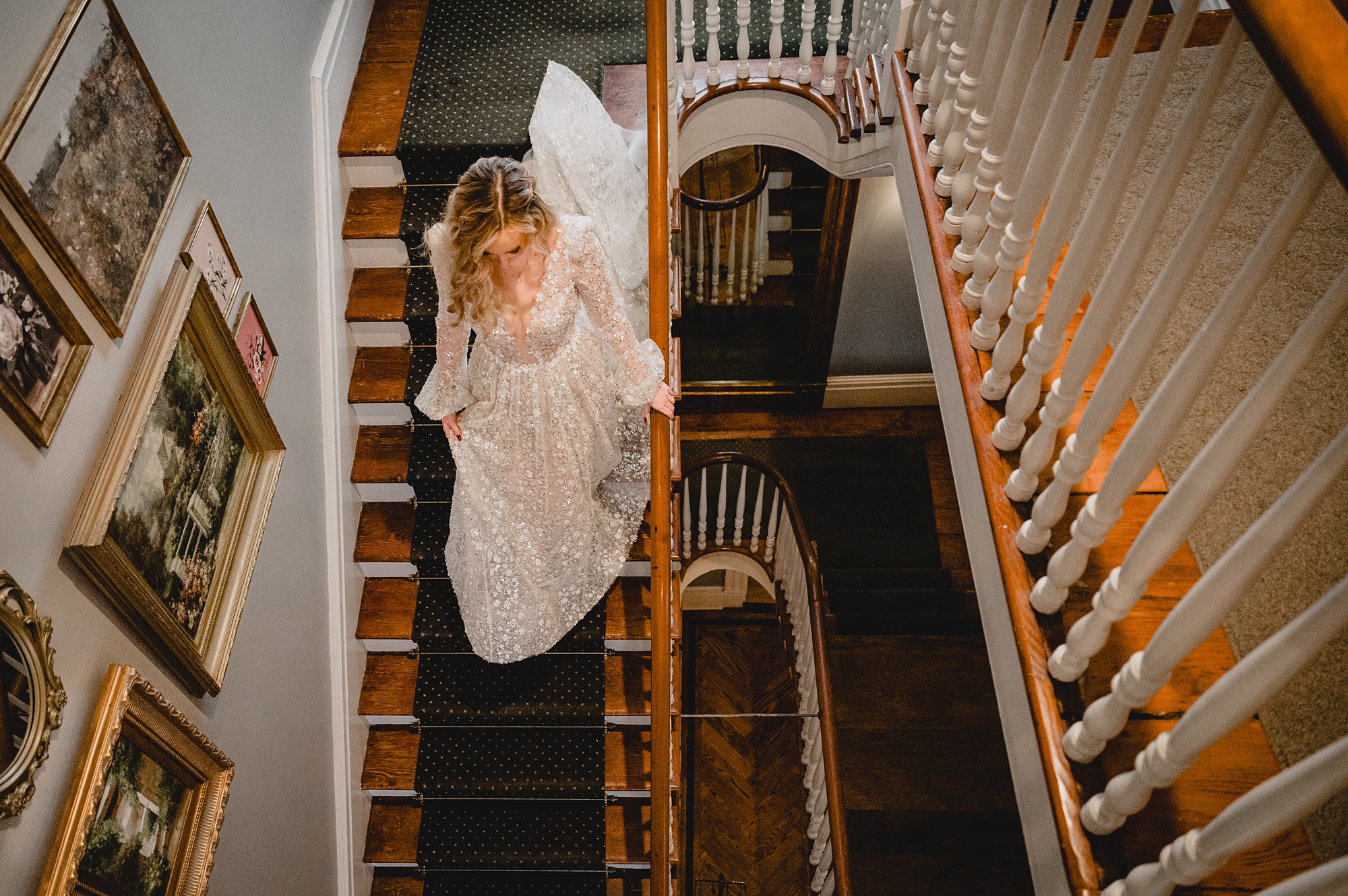bride walks down steps inside David's Country Inn with dress trailing behind her