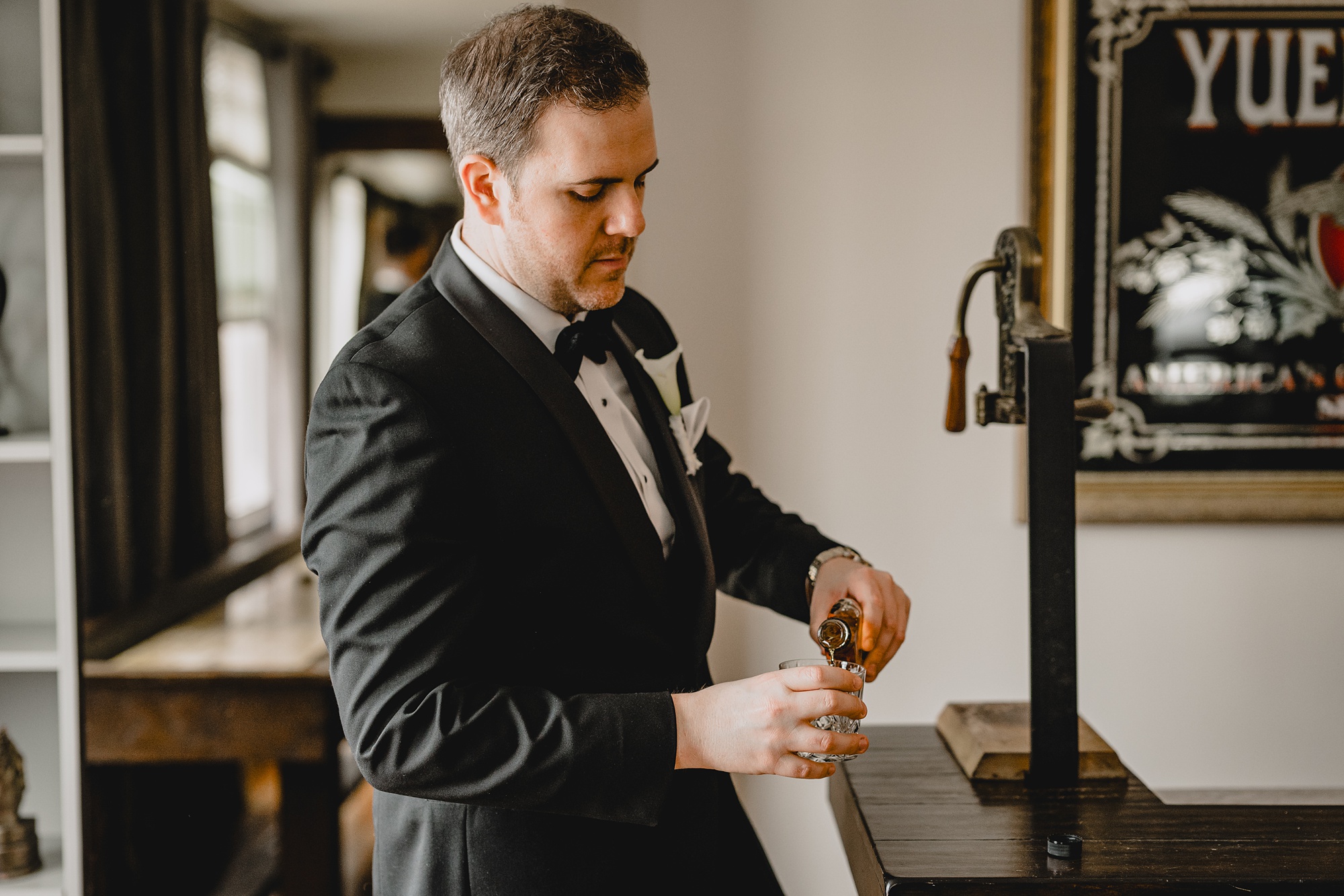 groom pours a drink of whiskey