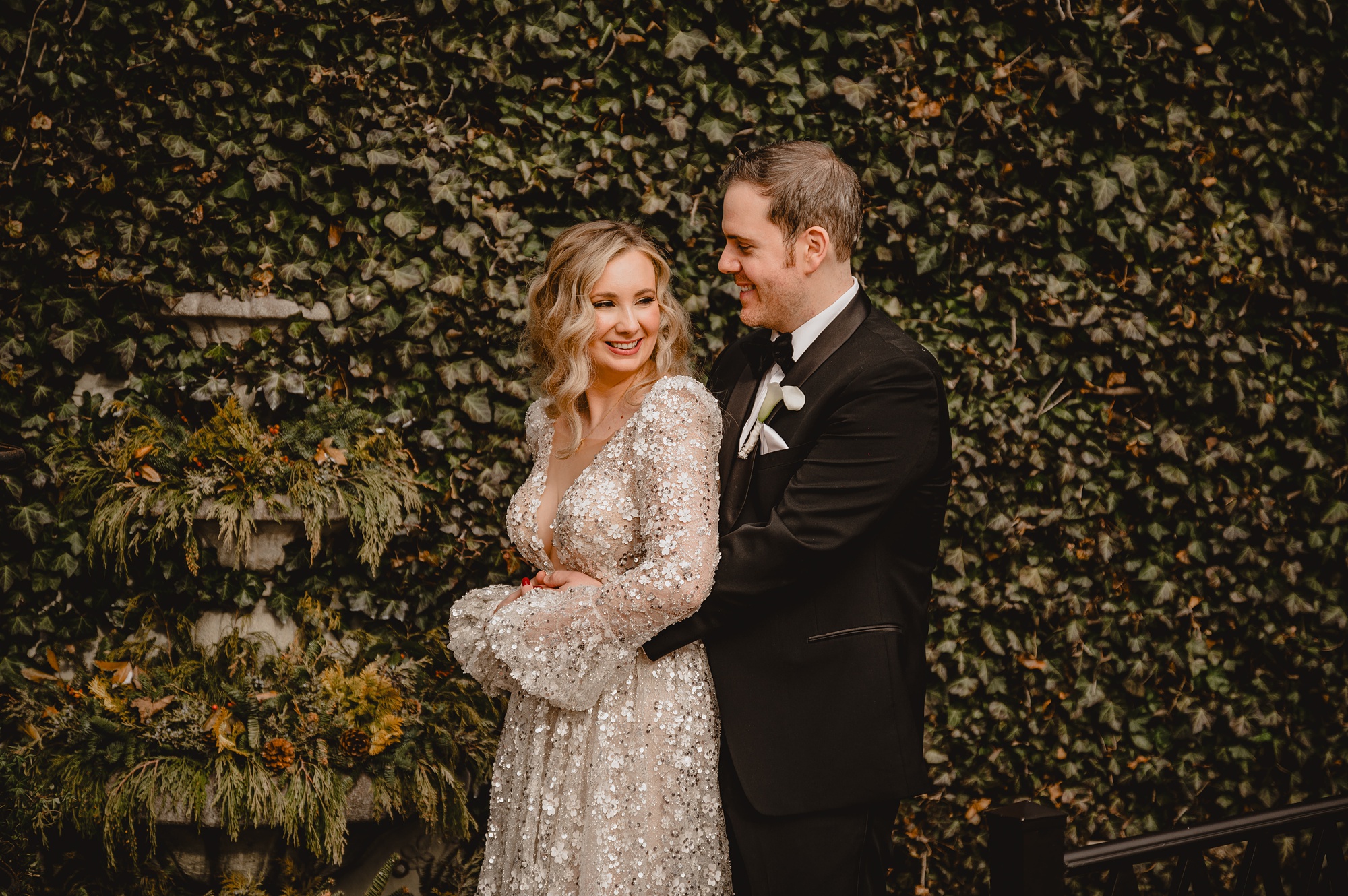 groom hugs bride from behind in front of ivy covered wall at David's Country Inn