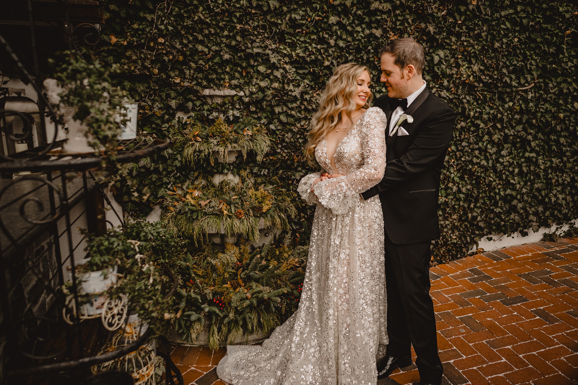 bride and groom hug by greenery covered wall at David's Country Inn