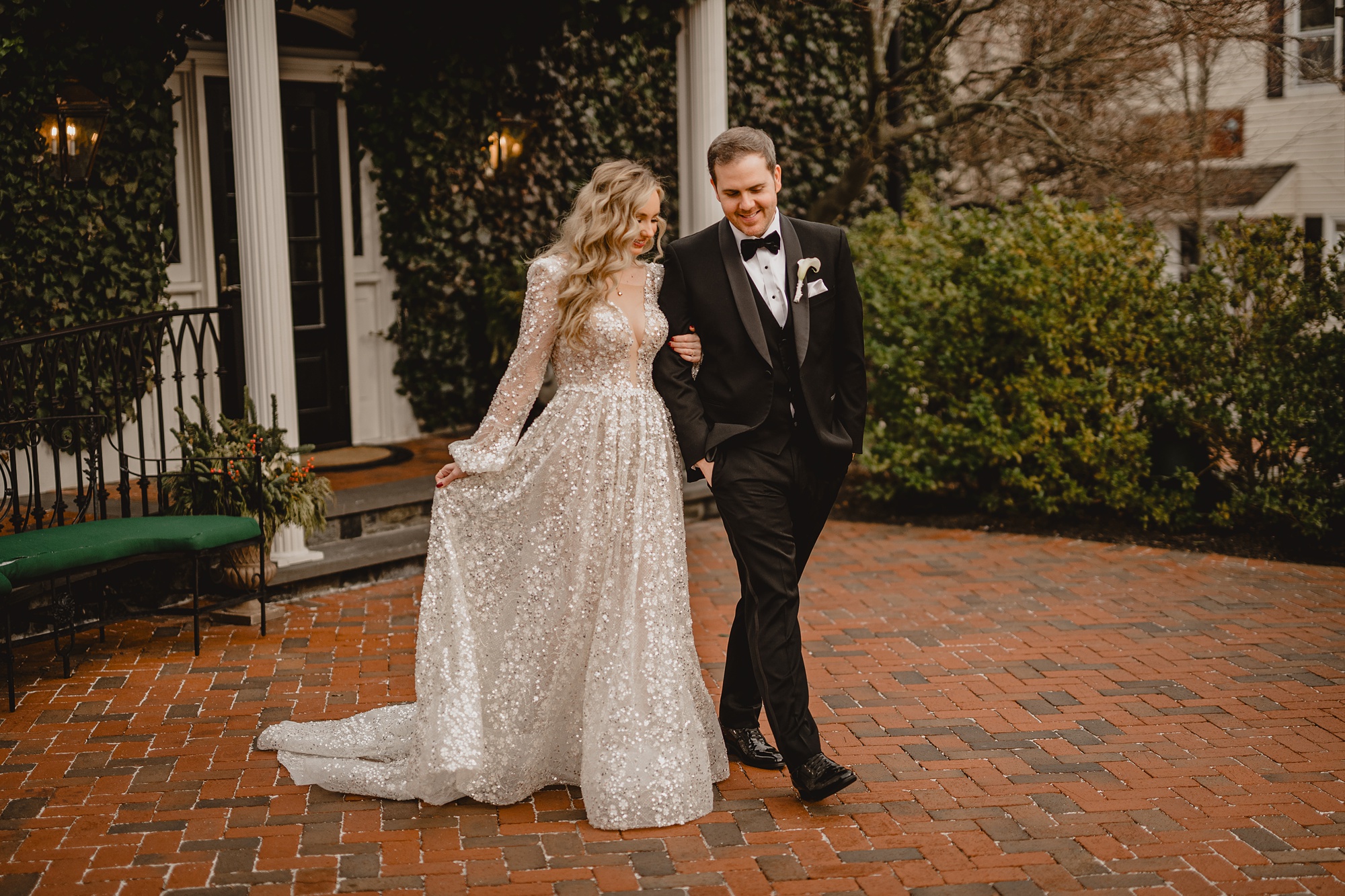 bride and groom walk across brick patio together