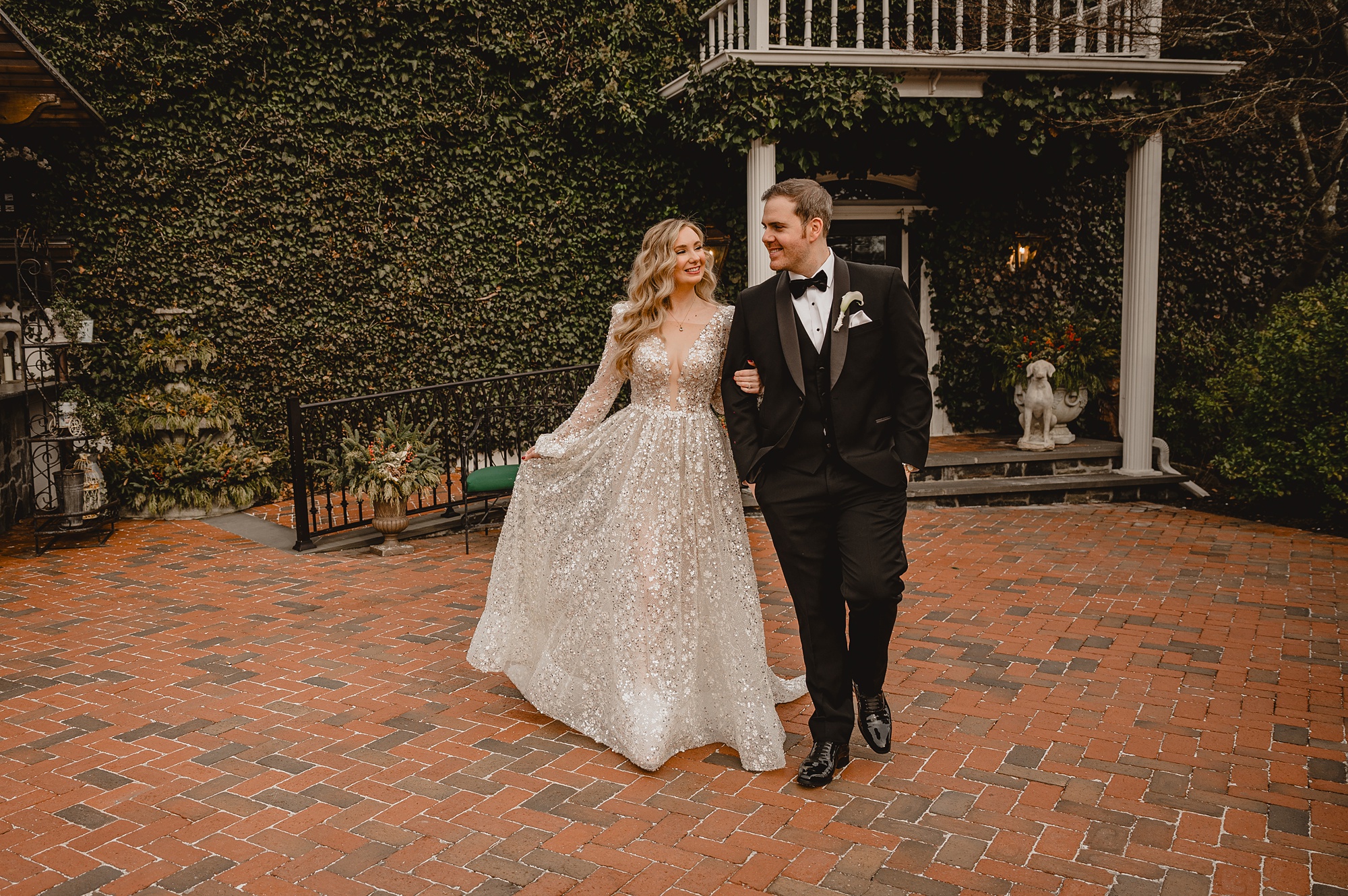 bride walks with groom holding his arm on brick patio at David's Country Inn