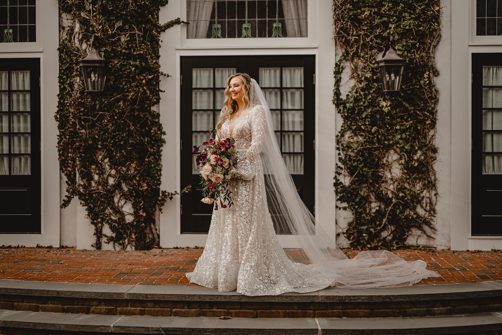 bride stands on patio at David's Country Inn with veil pulled out behind her