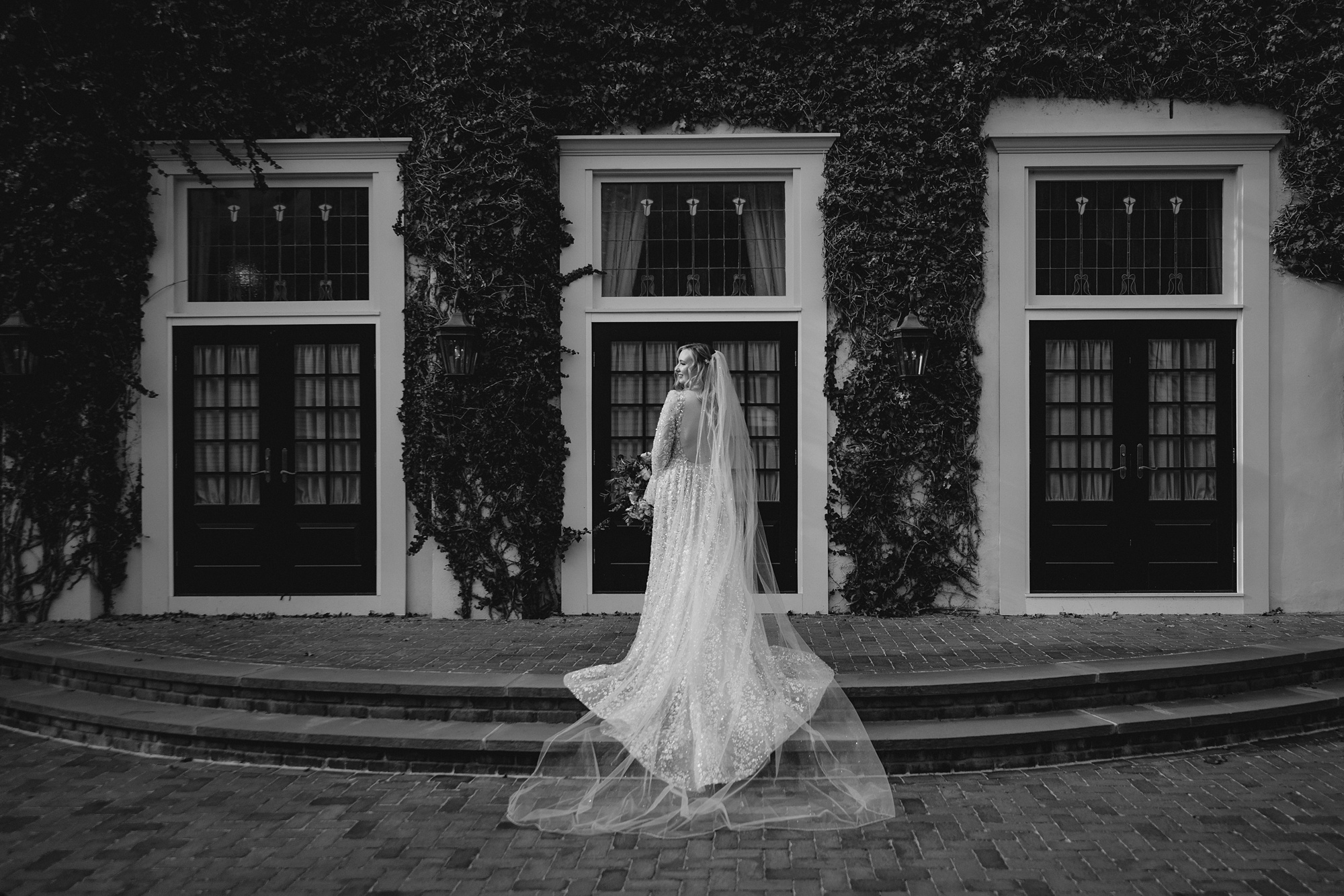 bride stands showing off back of wedding gown and veil