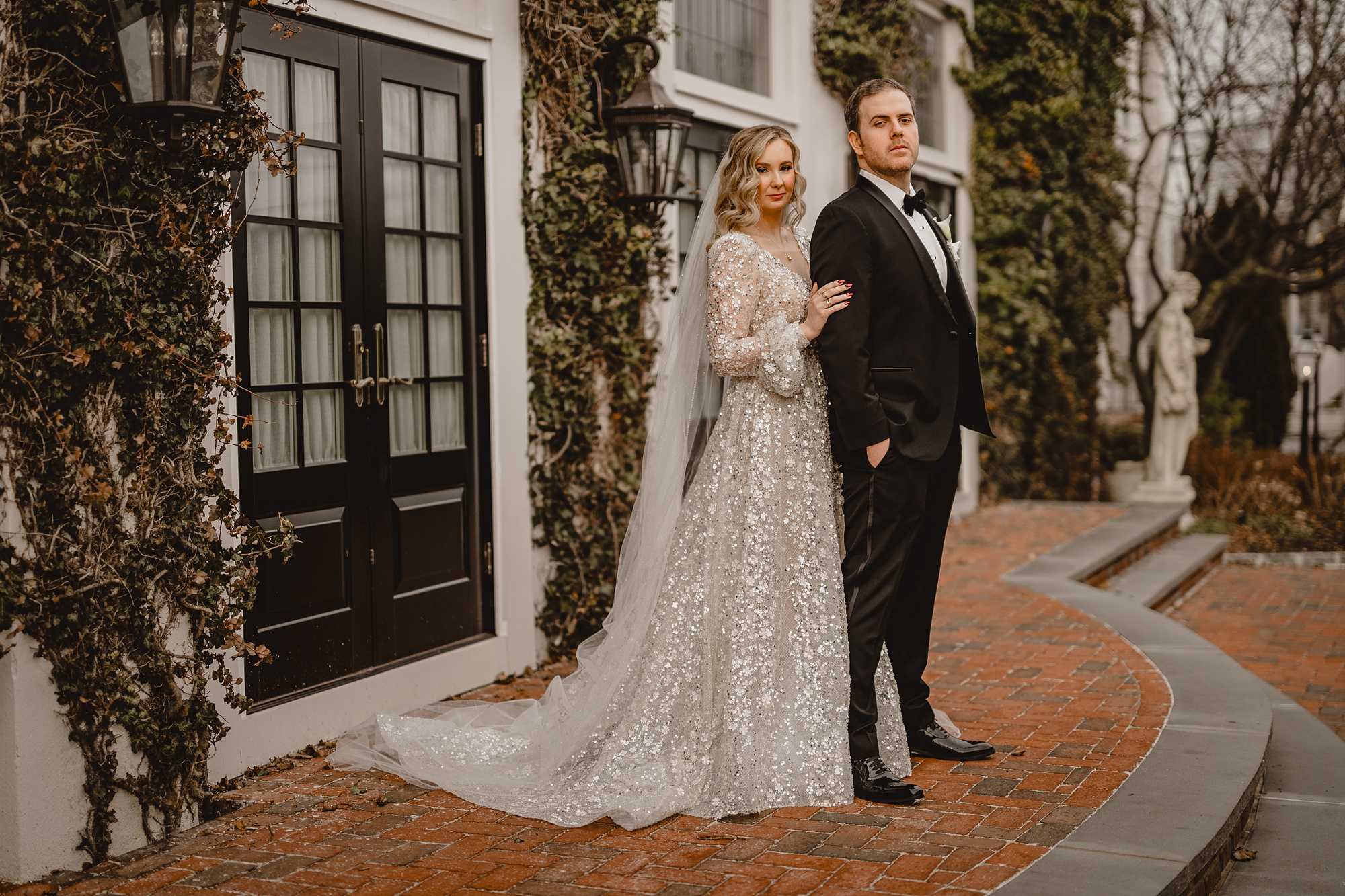 bride stands behind groom holding his arm on top step at David's Country Inn