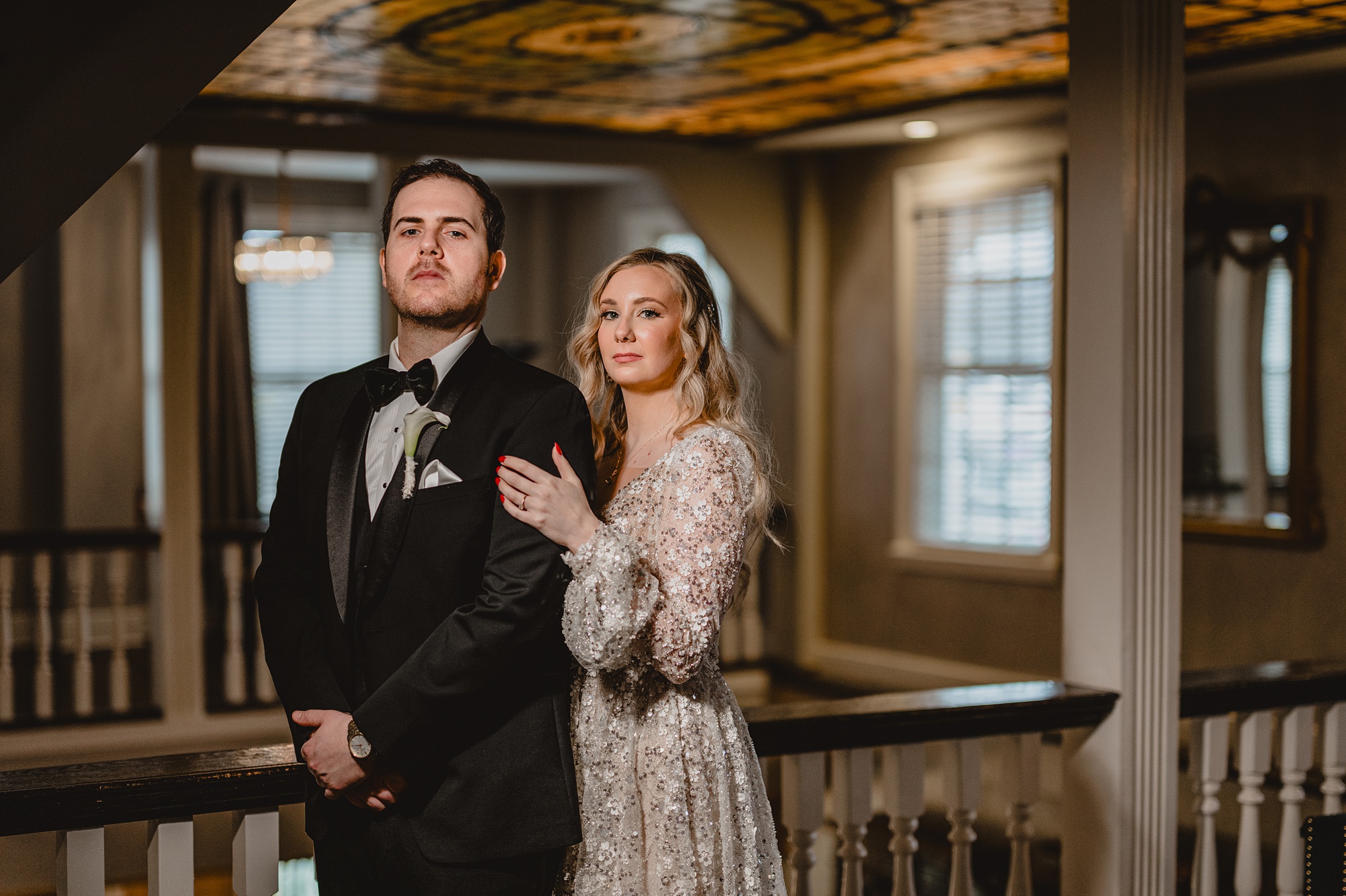 bride holds groom's shoulder standing behind him