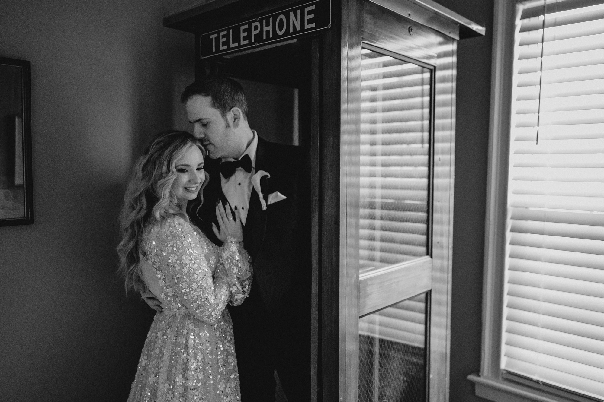 newlyweds hug against telephone booth inside David's Country Inn