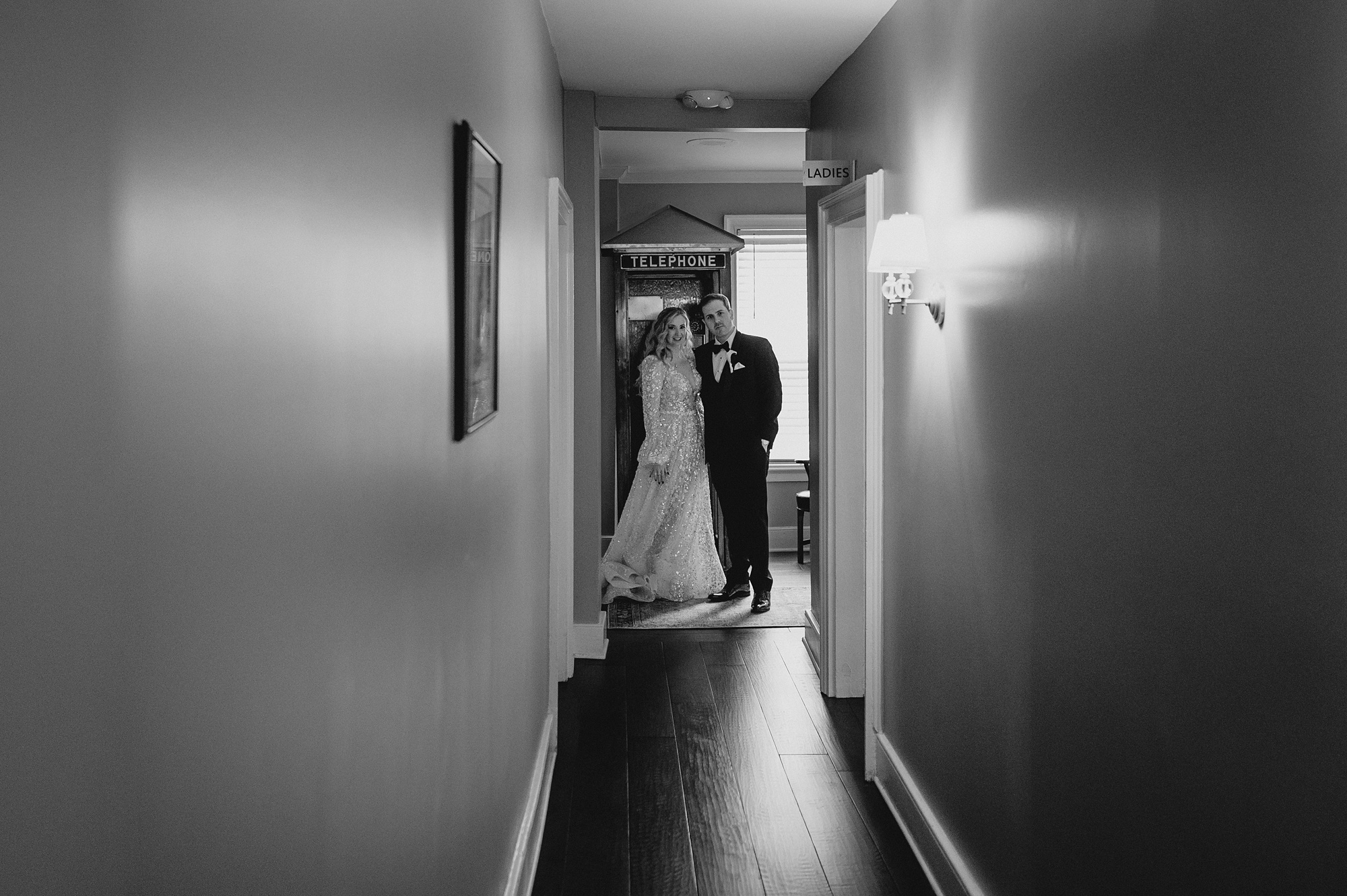 bride and groom hug at the end of a hallway