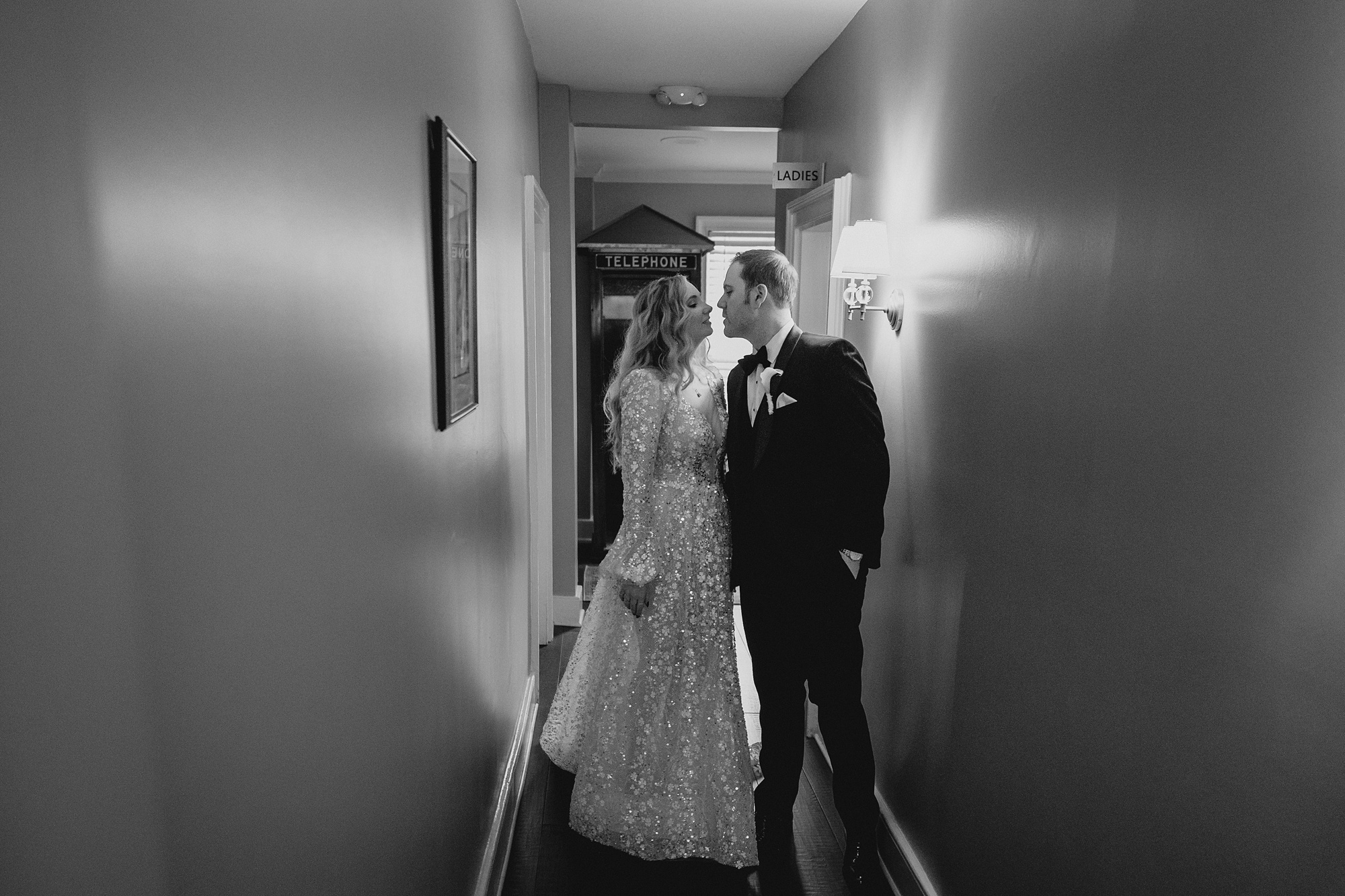 bride and groom lean for a kiss in the middle of the hallway