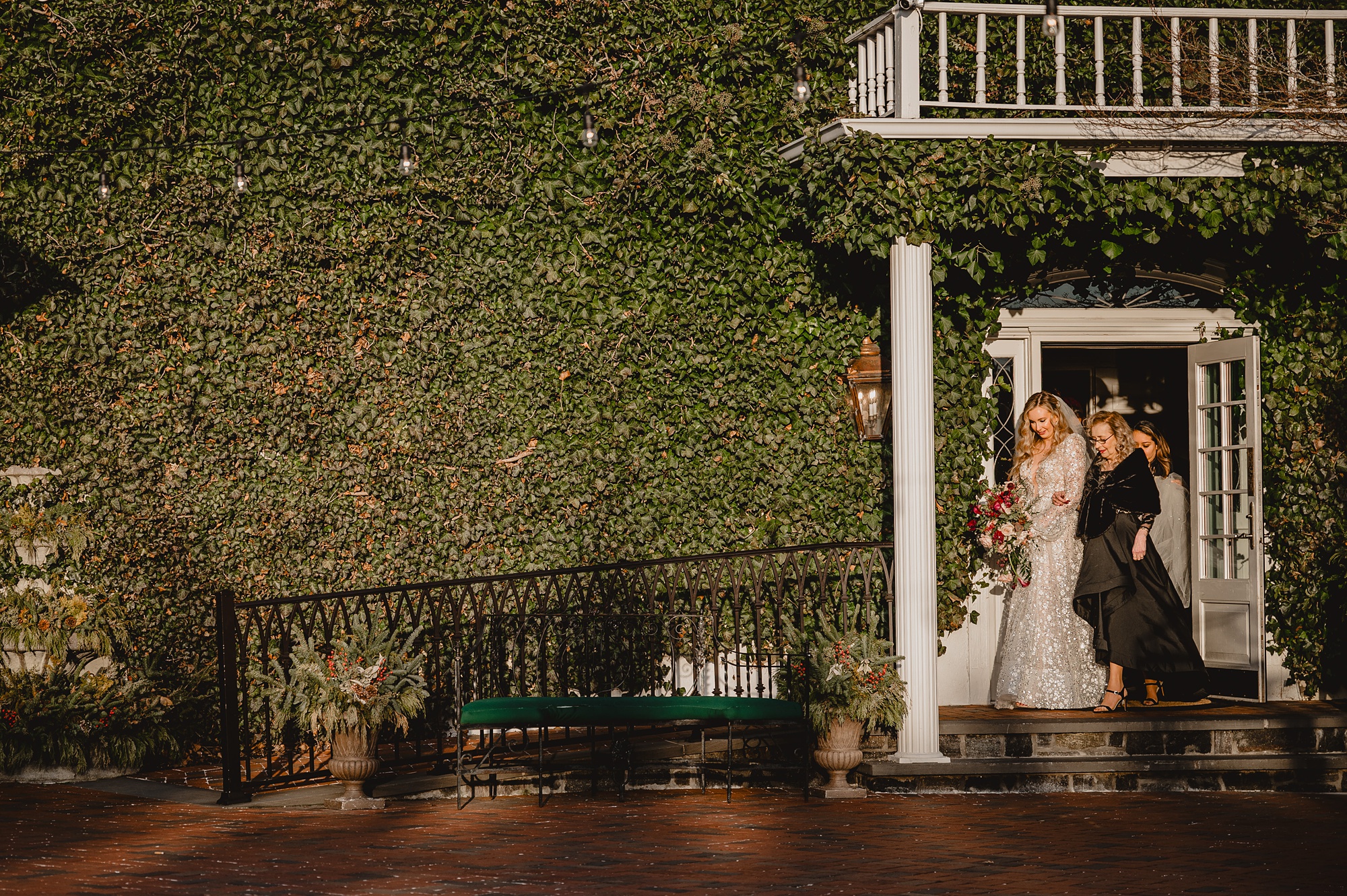 bride walks out of building with mother for winter wedding ceremony outside at David's Country Inn