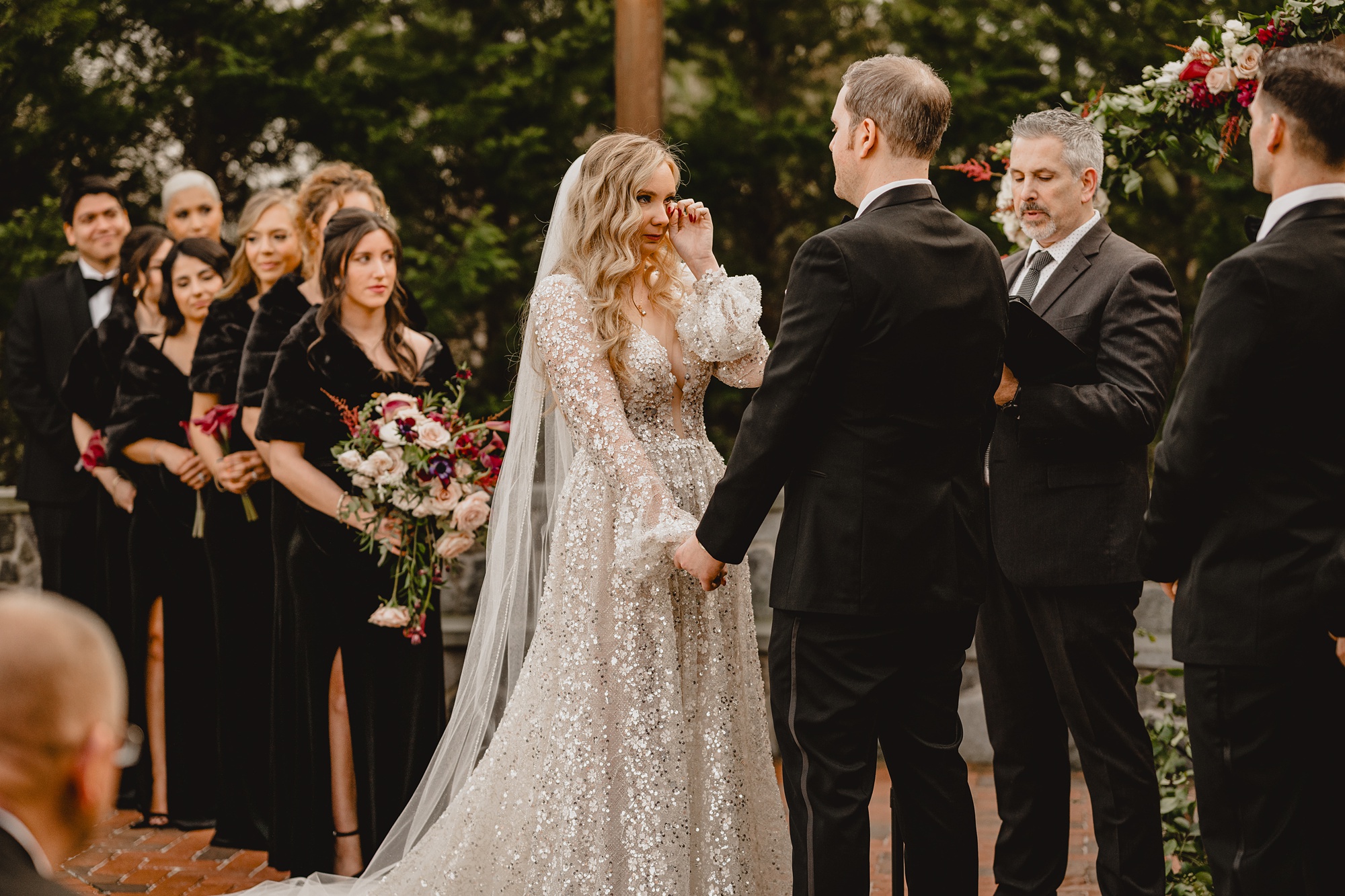 bride wipes eyes during winter wedding ceremony outside at David's Country Inn