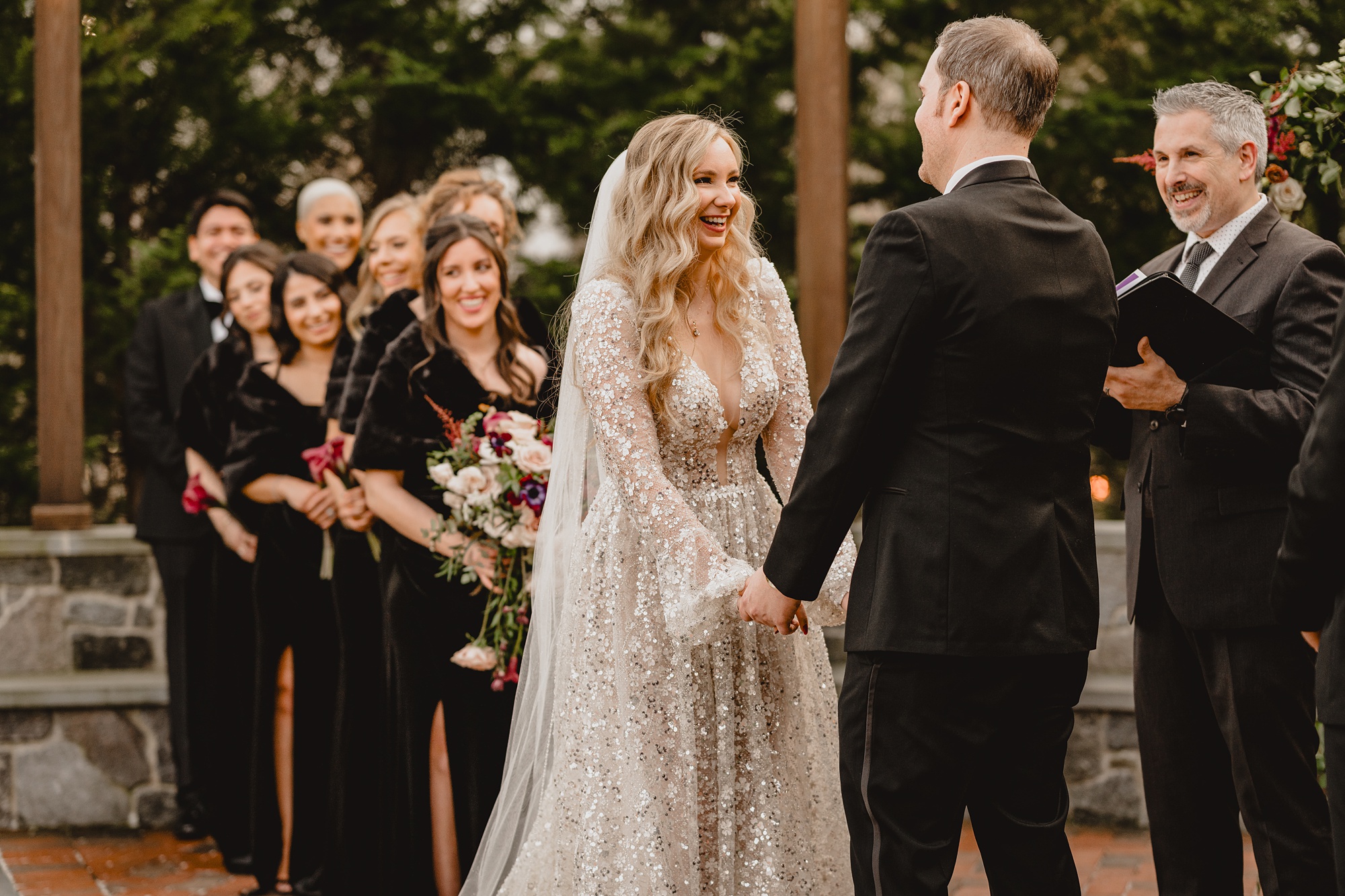 bride holds groom's hands smiling at him during winter wedding ceremony outside at David's Country Inn