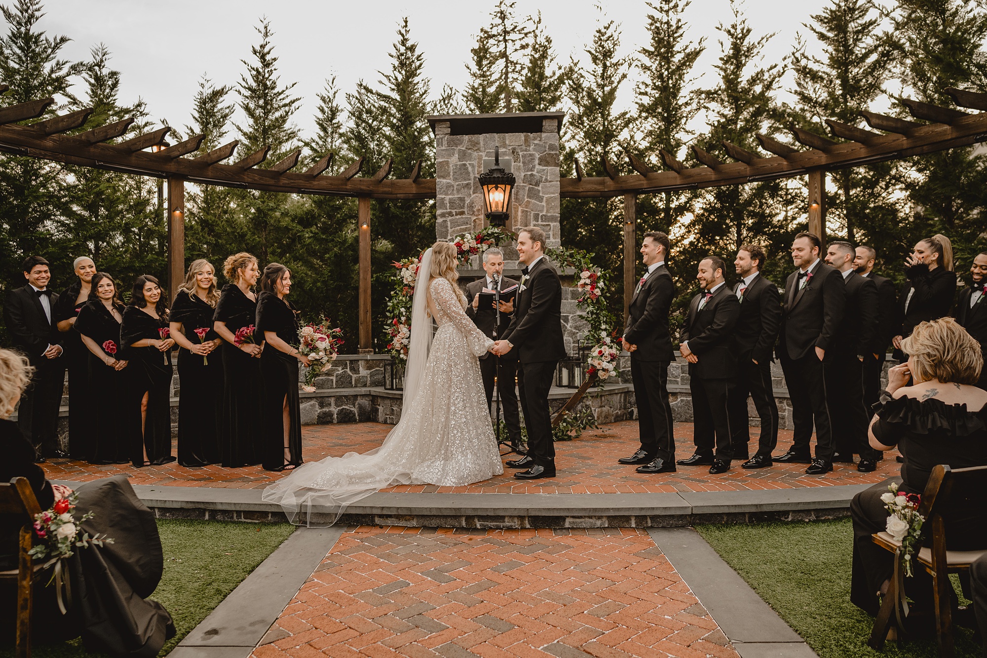 bride and groom hold hands with wedding party around them during winter wedding ceremony outside at David's Country Inn