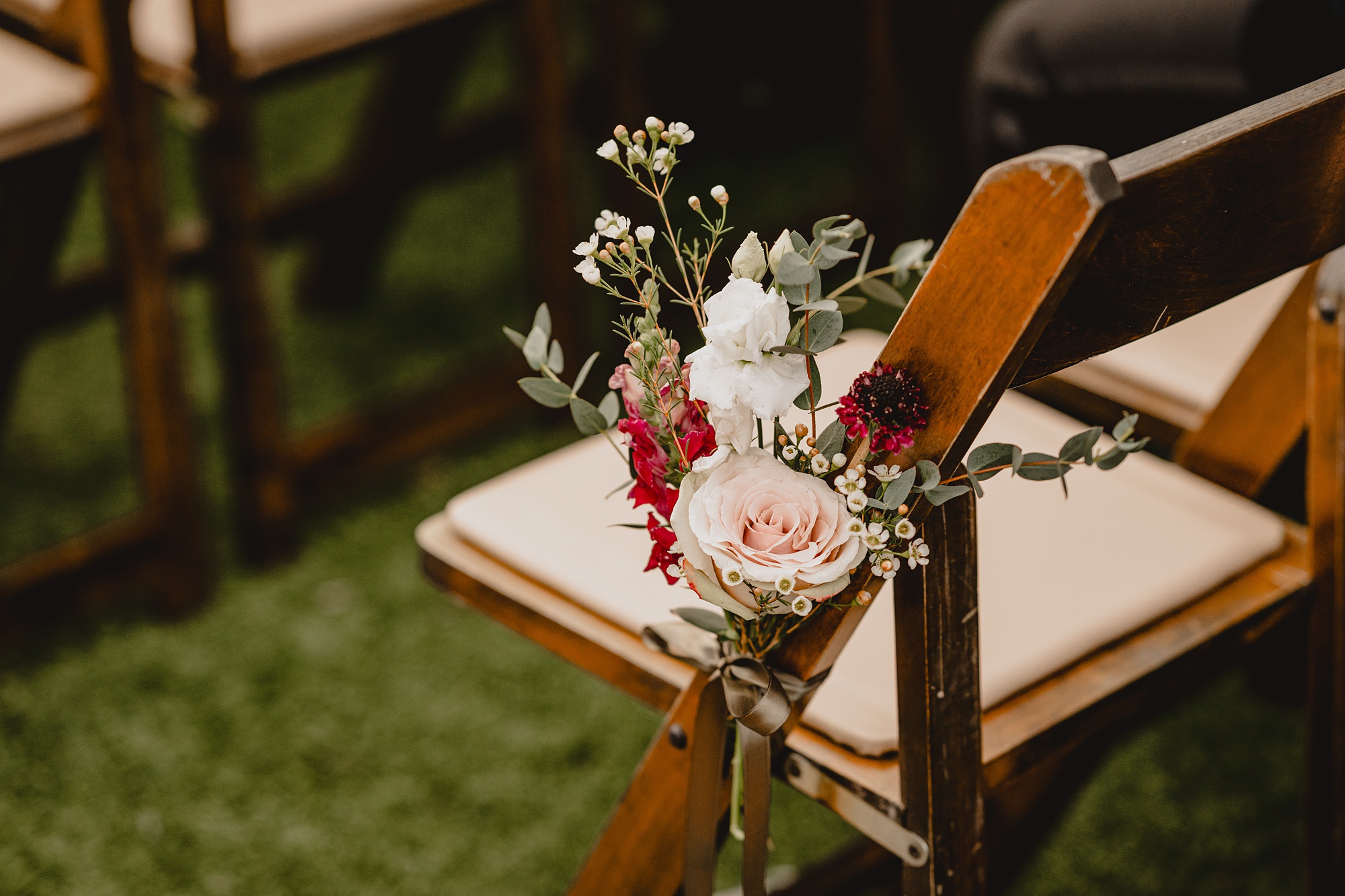 pink rose hangs on end of aisle on wooden chair