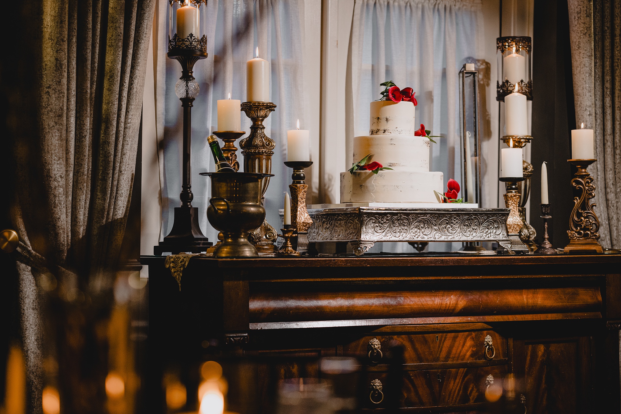 tiered wedding cake with red flowers sits on display
