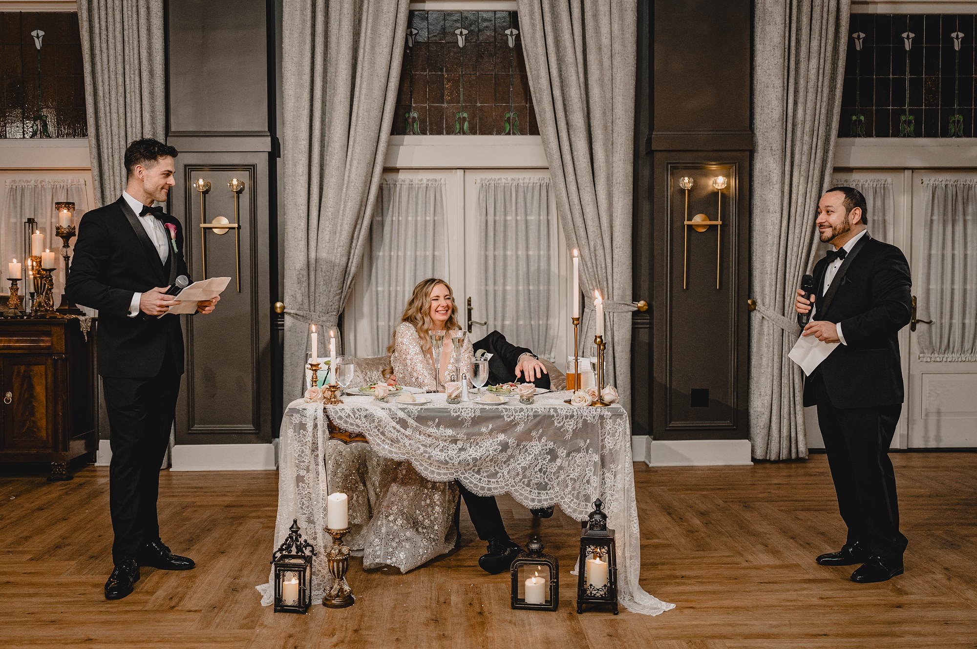 groom leans into bride laughing during speeches at reception