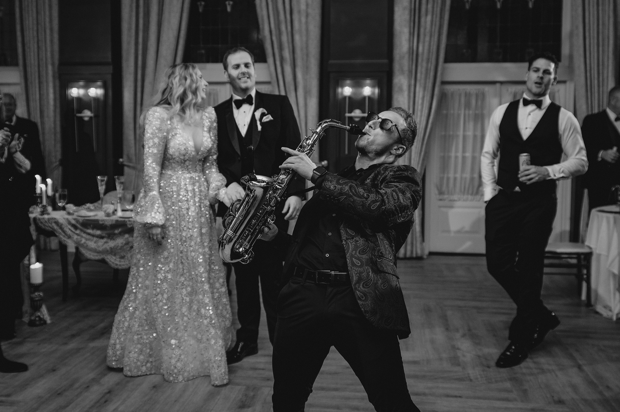 saxophone player performs in front of bride and groom on the dance floor