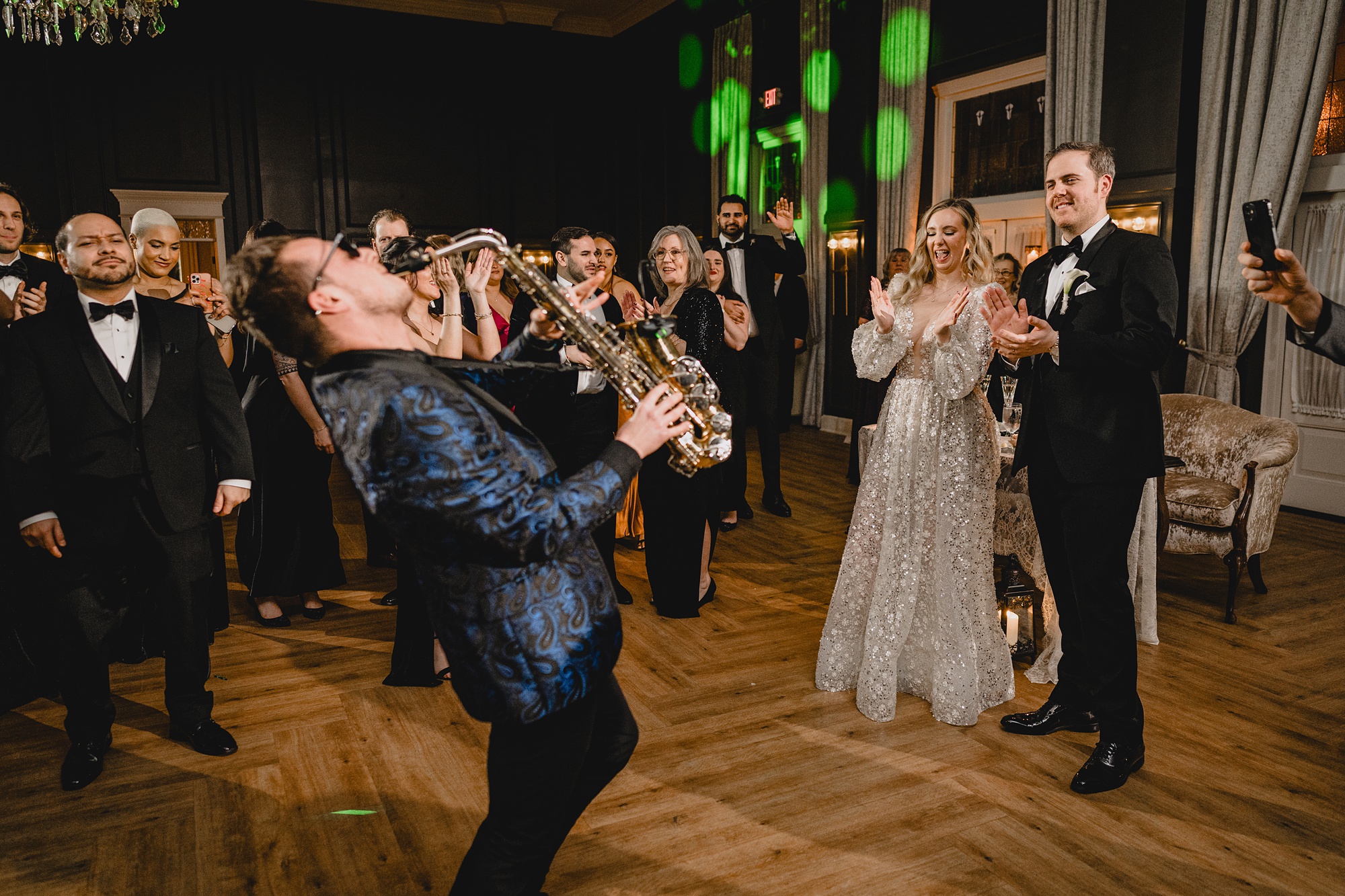 saxophone player performs in front of bride and groom on the dance floor