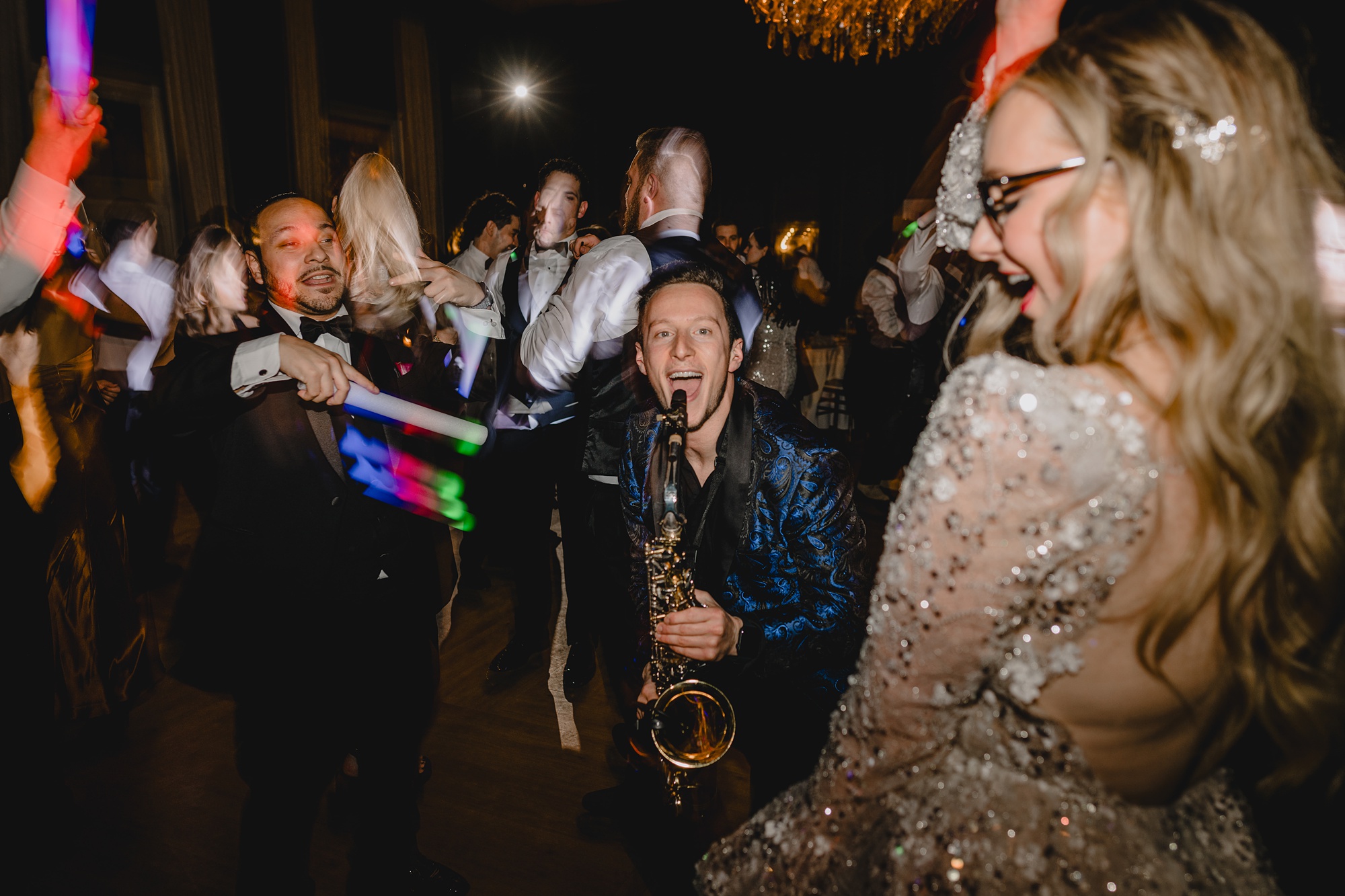 saxophone player performs in front of bride and groom on the dance floor