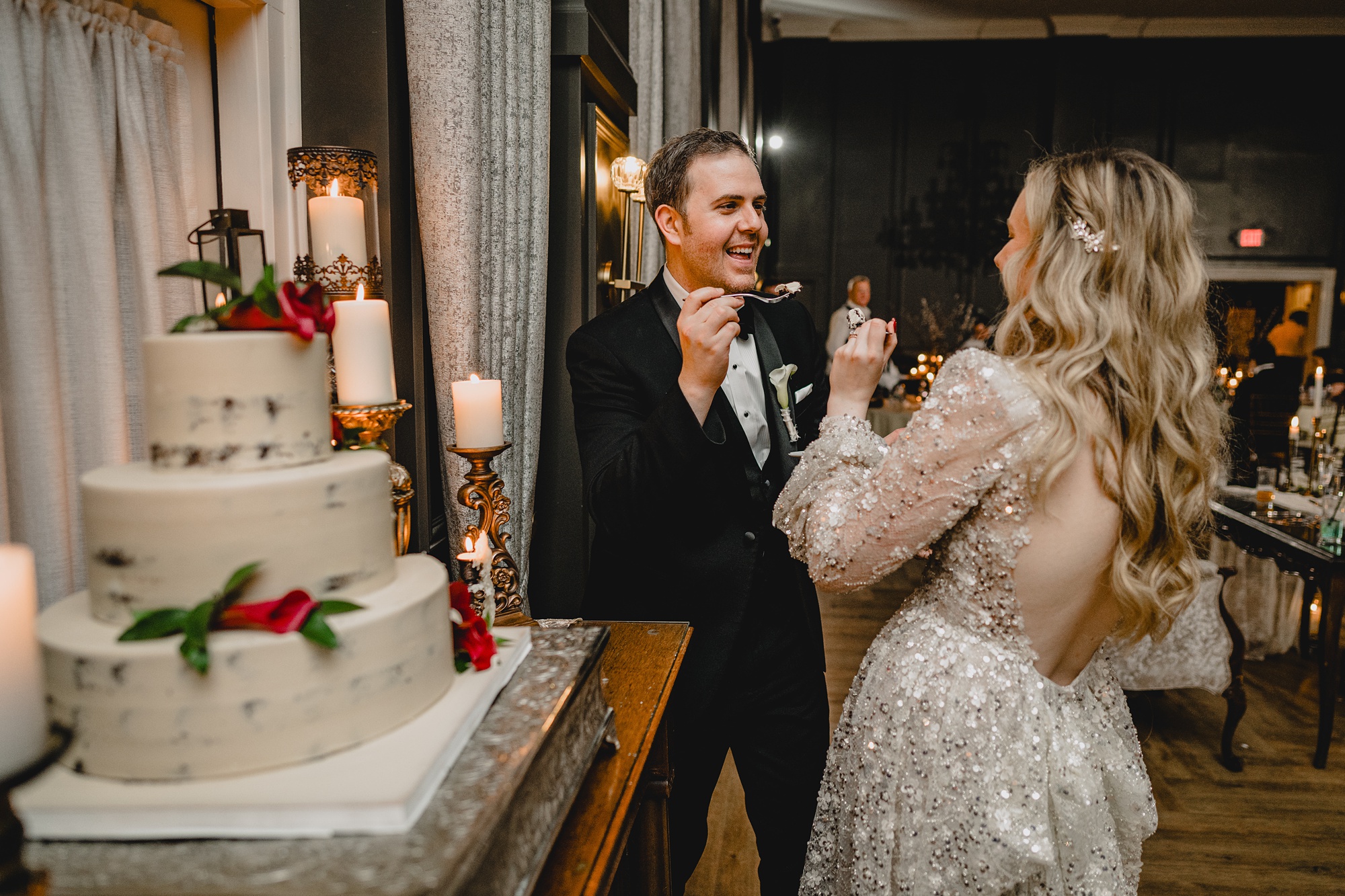 bride and groom cut wedding cake trying to feed each other