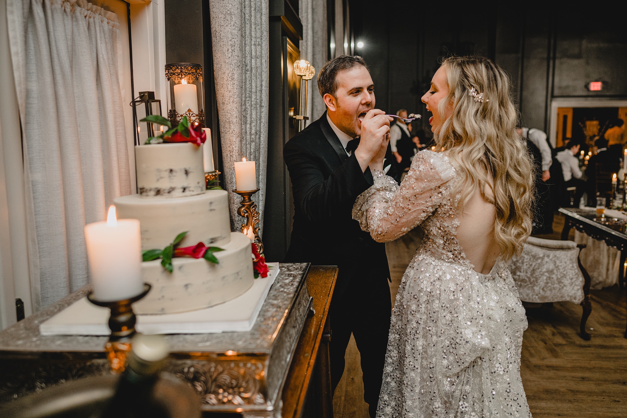 bride and groom cut wedding cake trying to feed each other