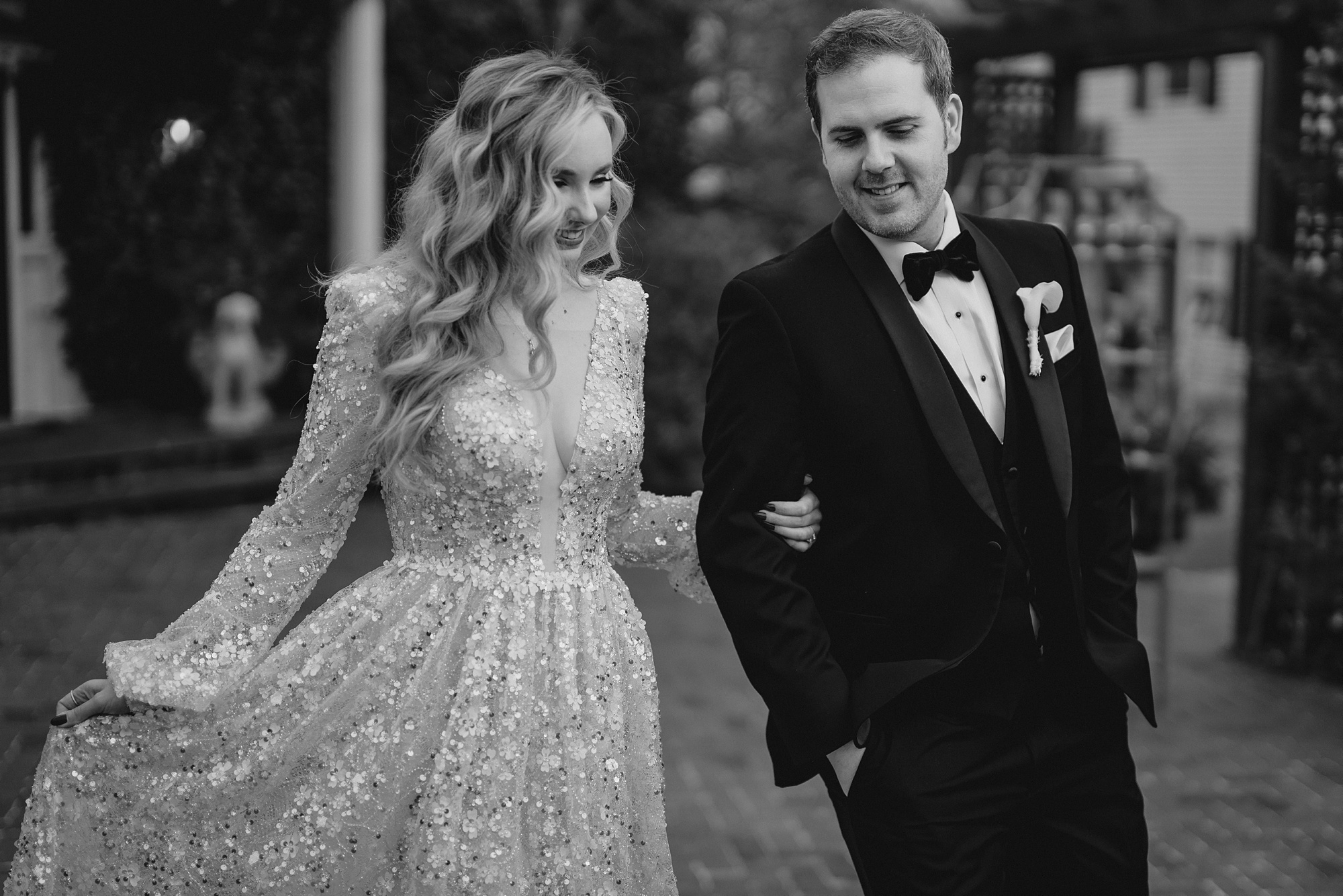 bride holds groom's arm walking on brick patio