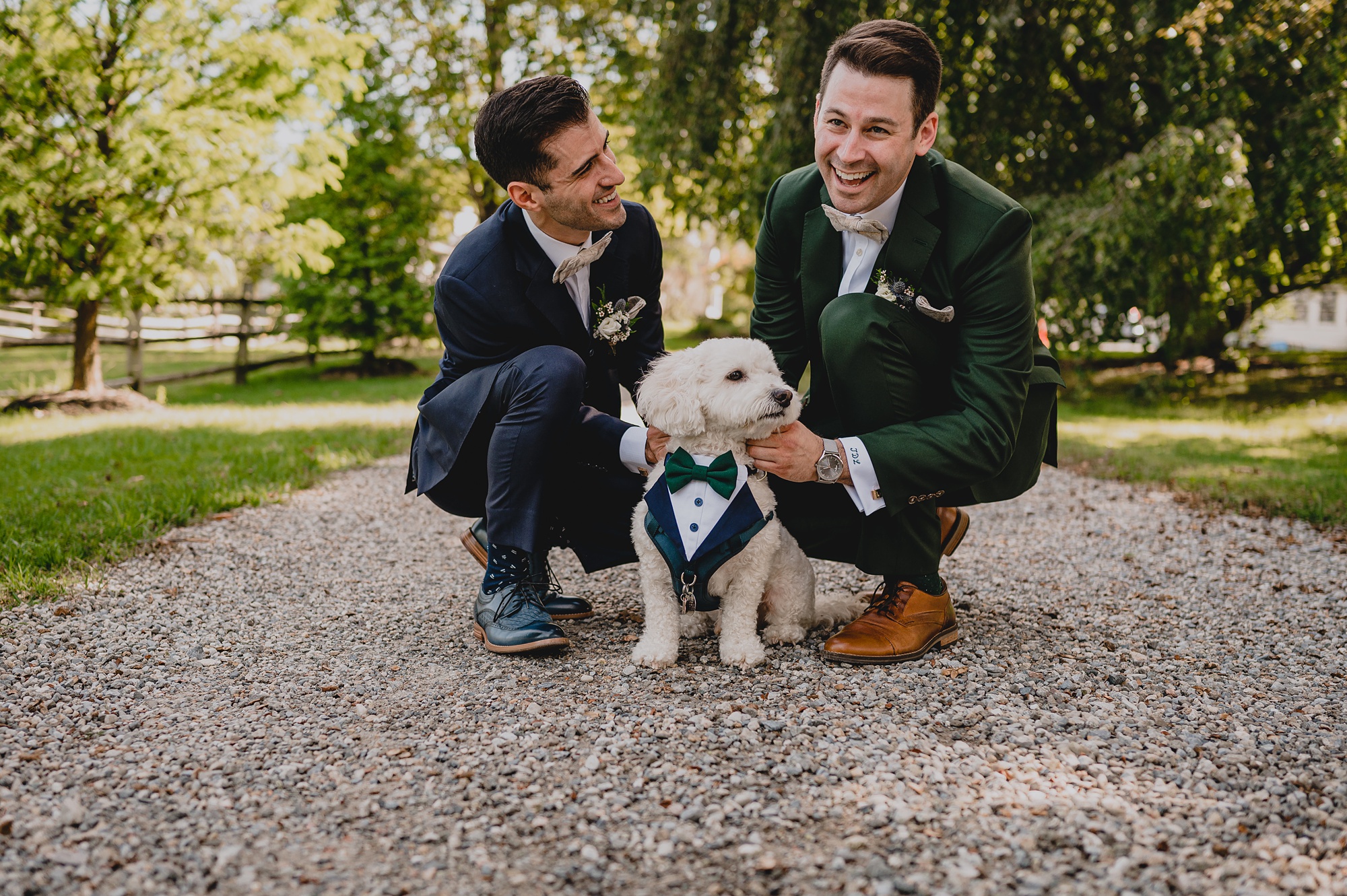 two grooms laugh with dog sitting on gravel driveway at Crossed Keys Estate