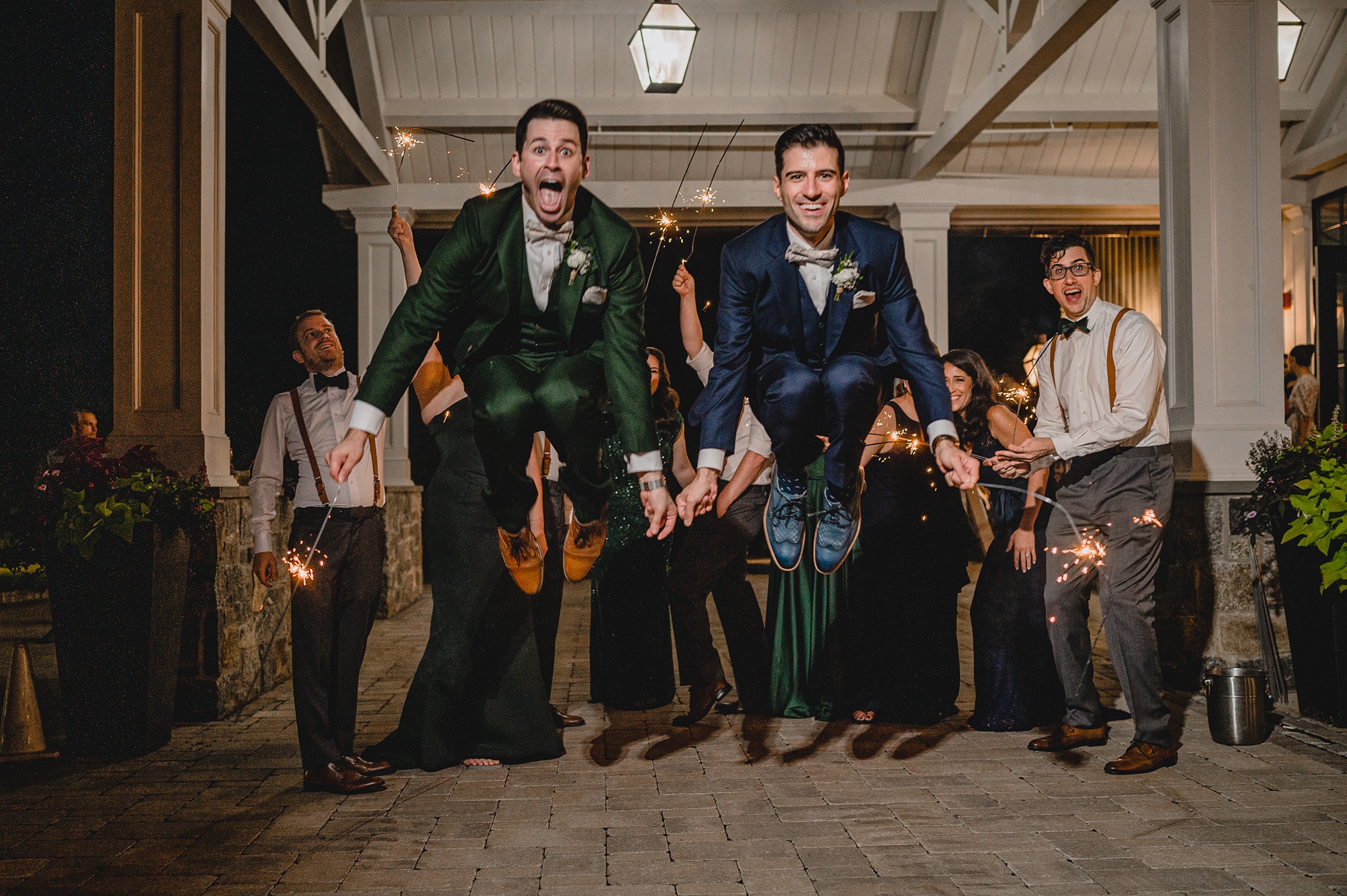 grooms jump holding sparklers outside Crossed Keys Estate