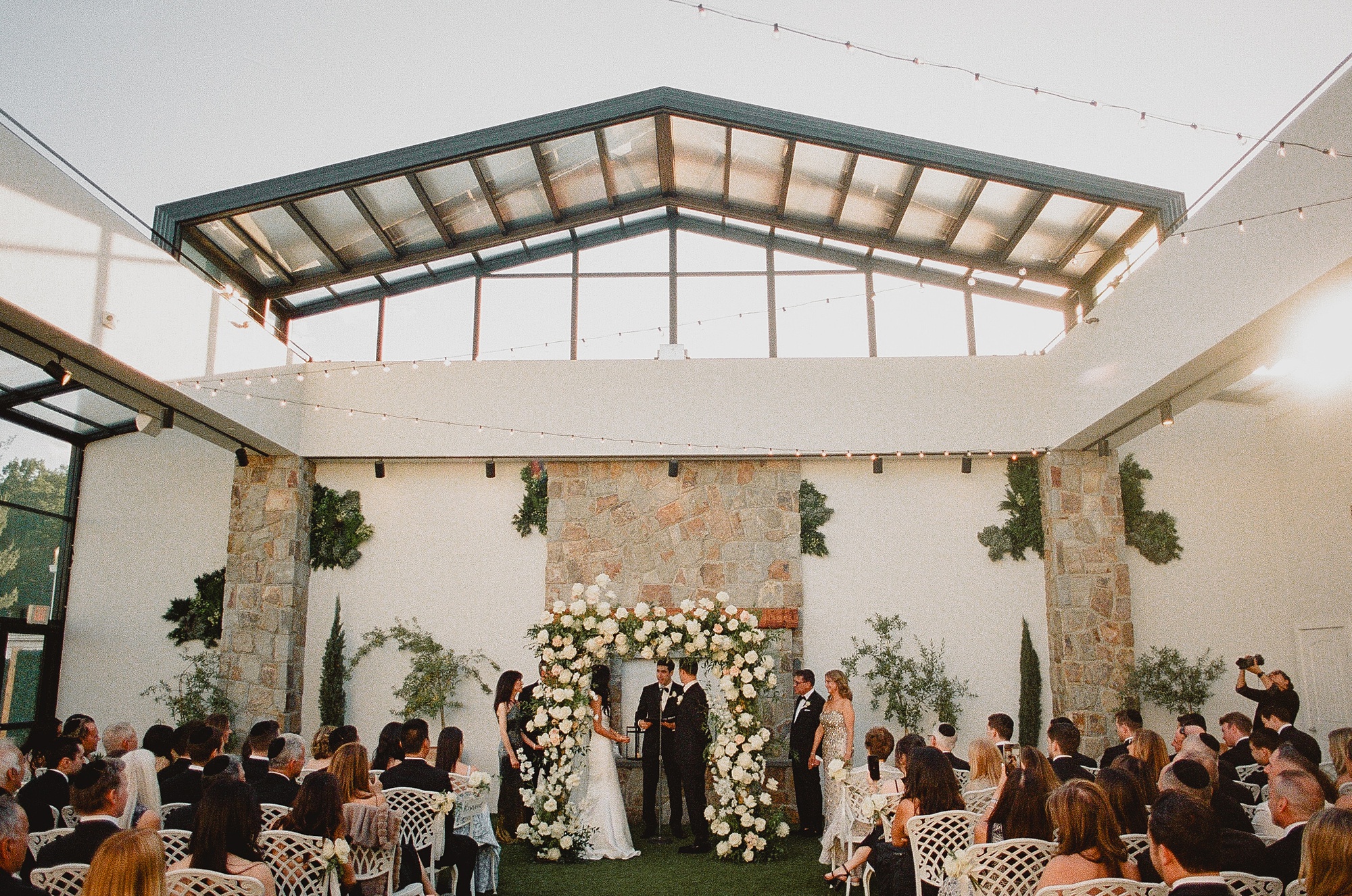 bride and groom hold hands during ceremony in open air atrium at Perona Farms