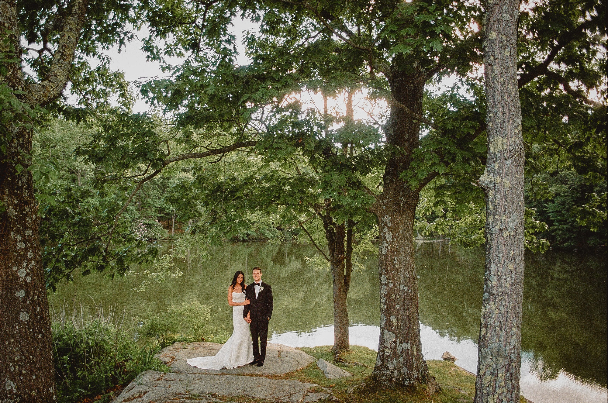 bride and groom hug under tree near river at Perona Farms