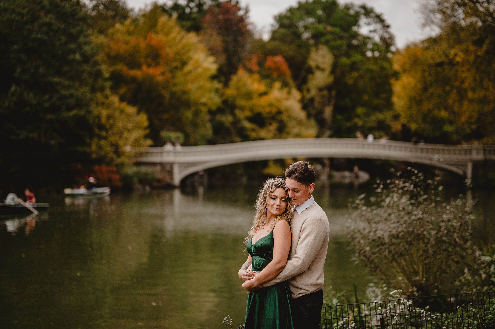man hugs woman in front of Bow Bridge 