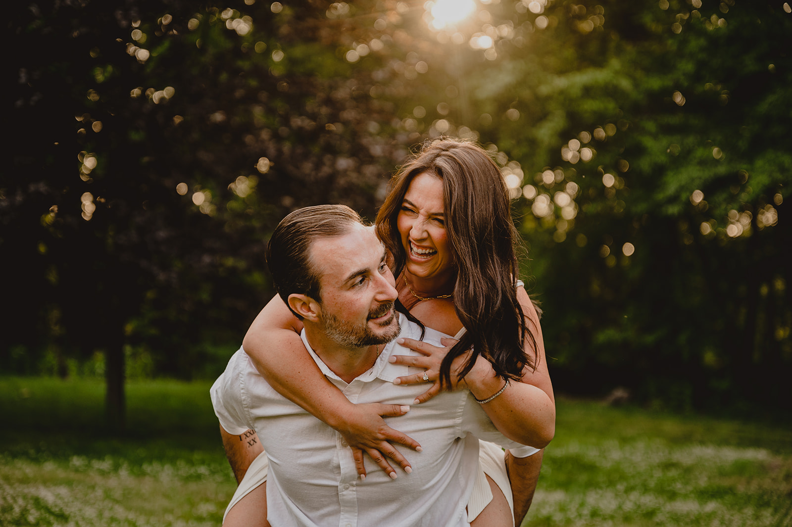 man gives woman a piggy back ride during summer engagement photos