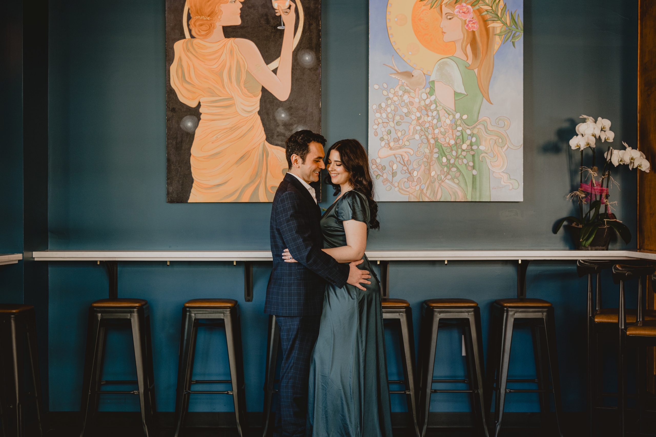 man and woman hug in front of bar and artwork in NYC