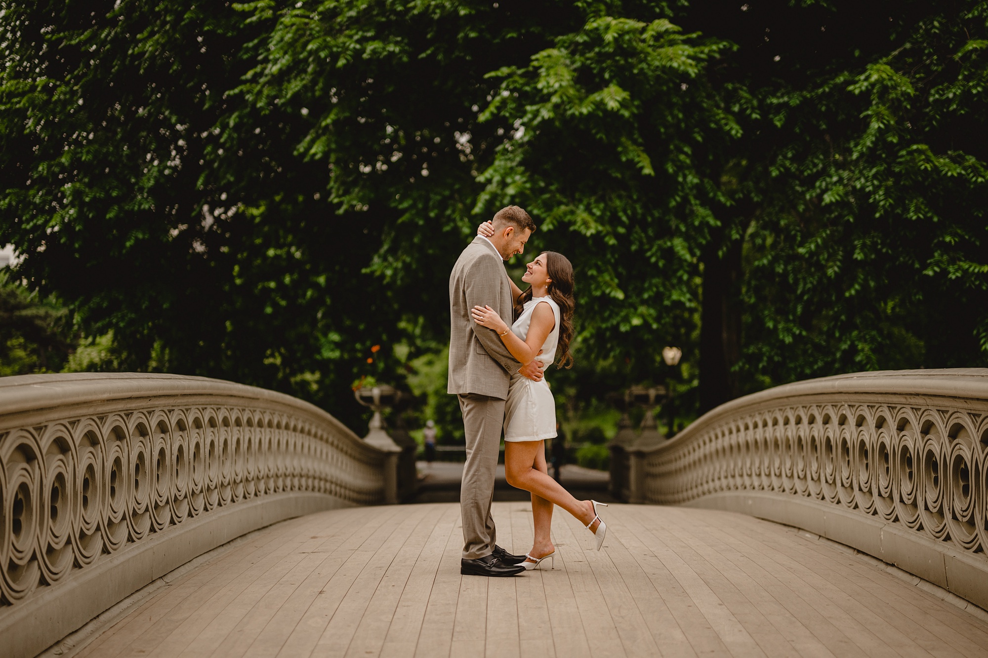couple hugs on bridge in Central Park during engagement session