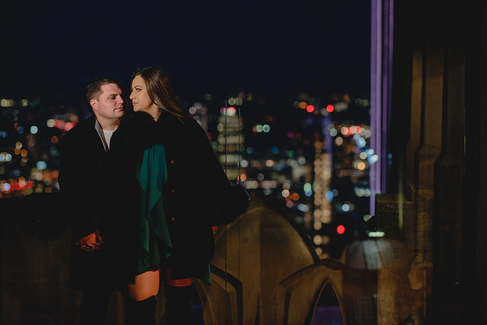 woman stands next to fiancee with NYC skyline lit behind them