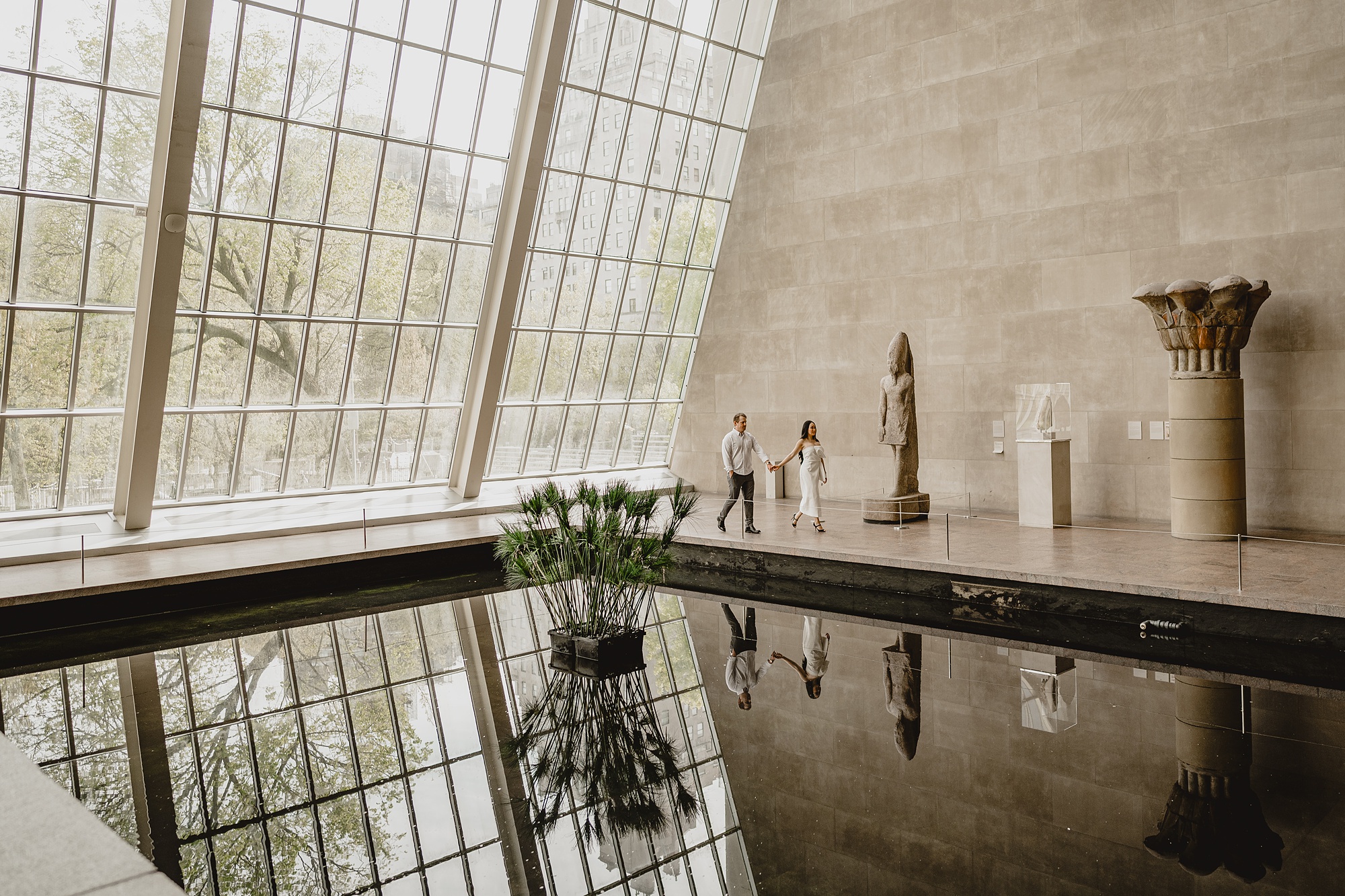 engaged couple walks around pond inside the Met