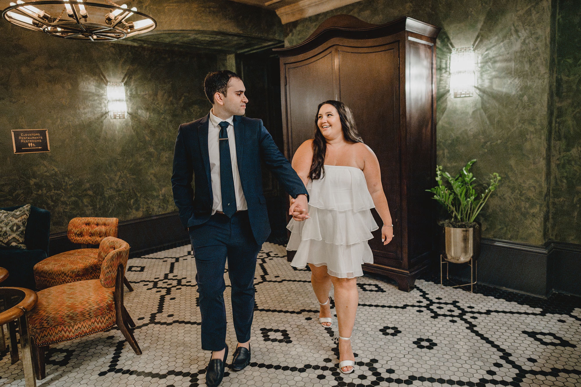 engaged couple holds hands walking through lobby of the Beekman Hotel