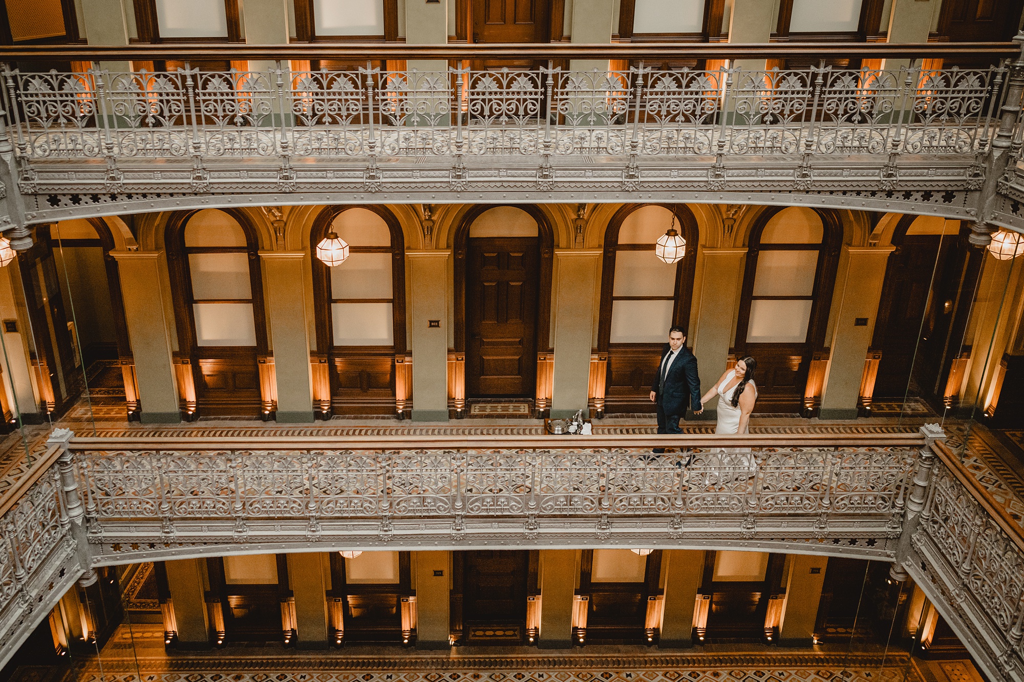 man and woman hold hands walking down hallway at the Beekman Hotel